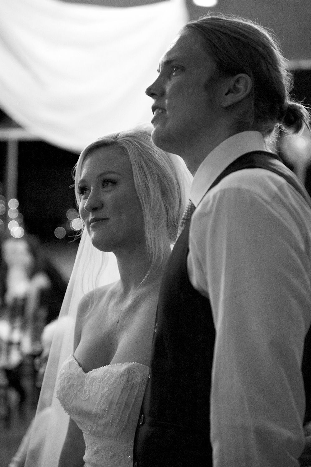 Monochrome photo of bride and groom exchanging a quiet look during their ceremony. Photo by Raymond Mather.