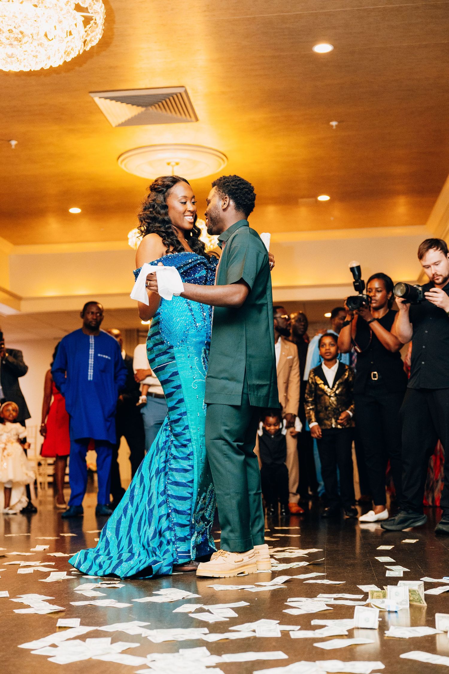 Couple sharing romantic first dance surrounded by guests at African wedding.