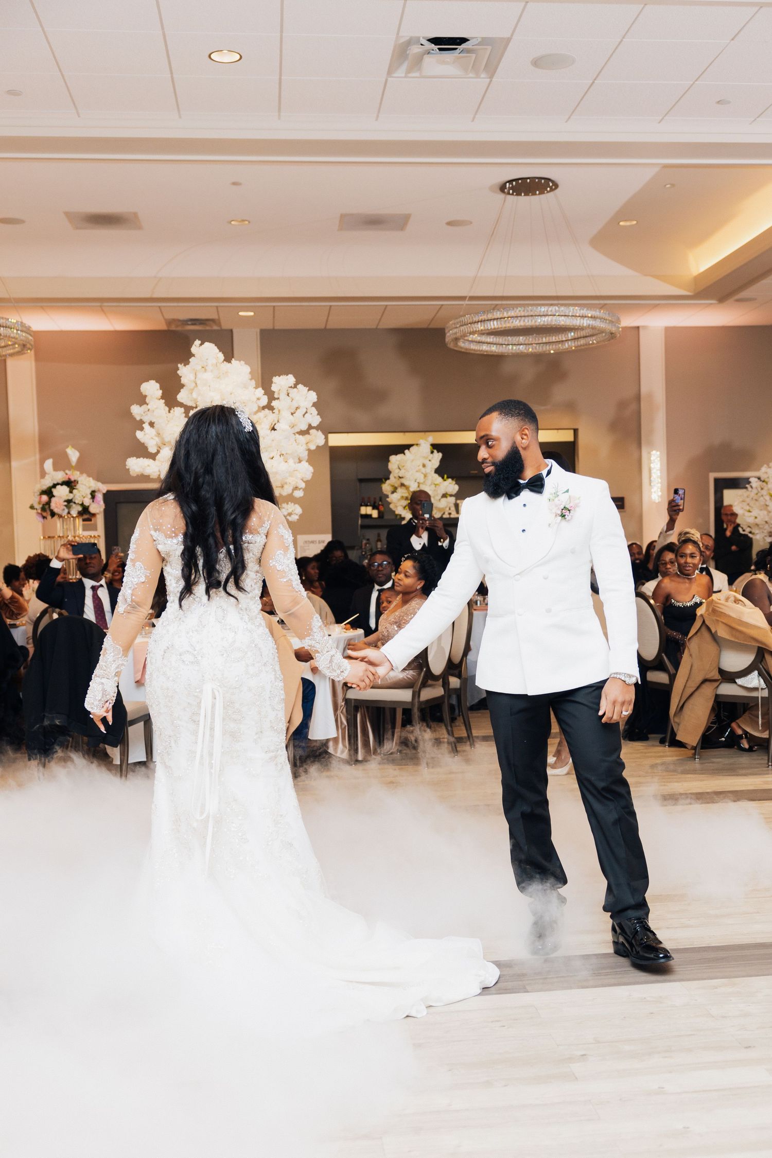 Bride and groom share their first dance on a fog-covered dance floor at their elegant wedding reception.