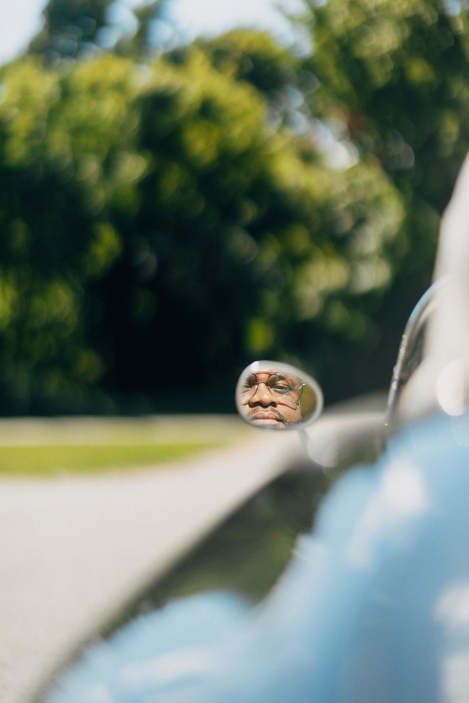 Reflection of a groom in the side mirror of a vintage black convertible wedding car.