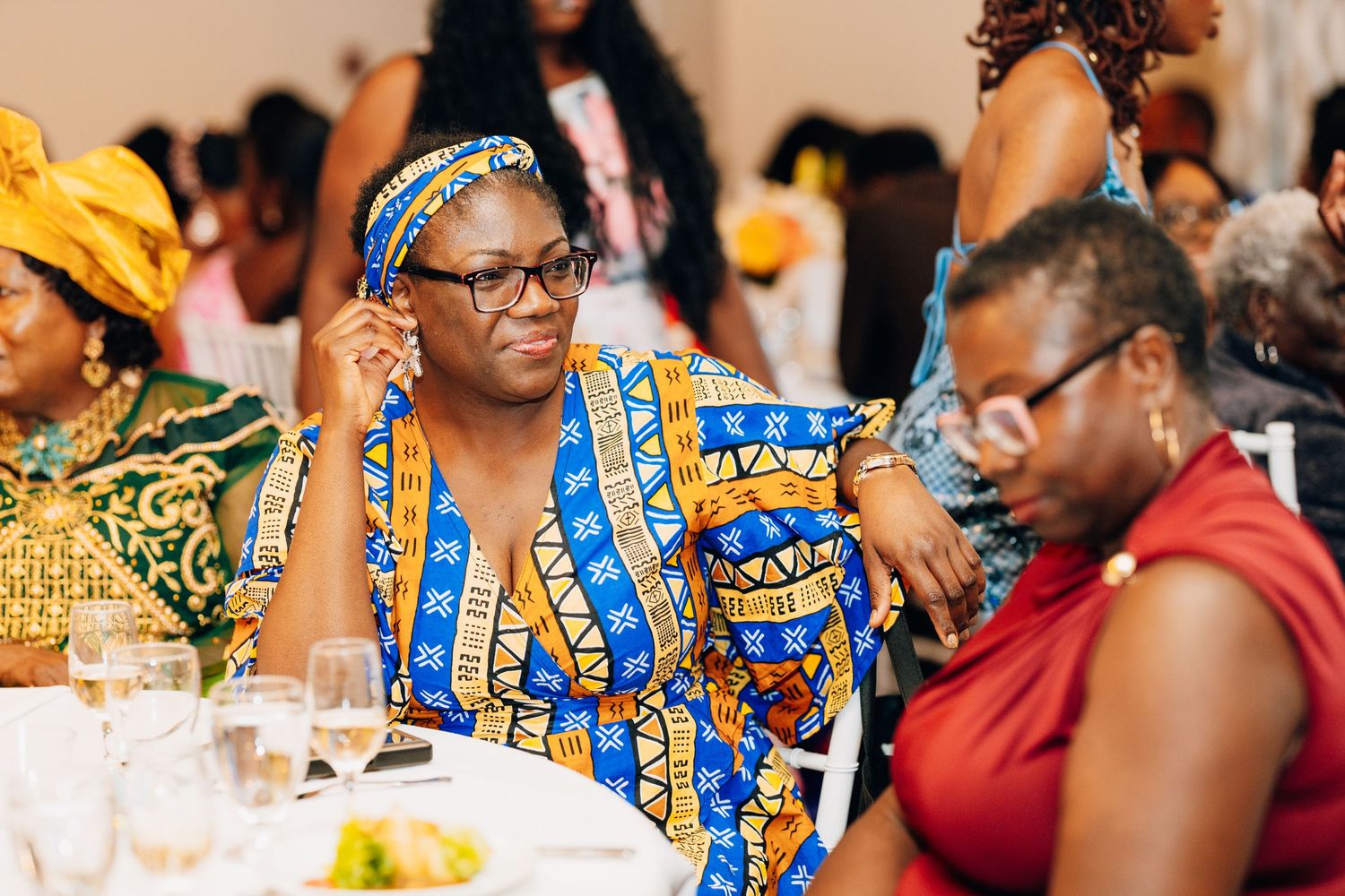 Guests in colorful African print attire seated at a wedding reception table.