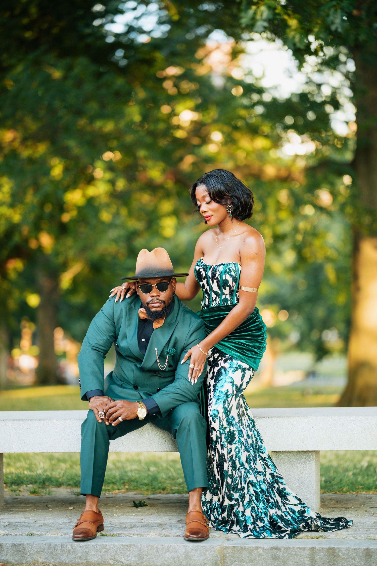 Stylish couple in matching emerald green outfits posing in a lush park setting.