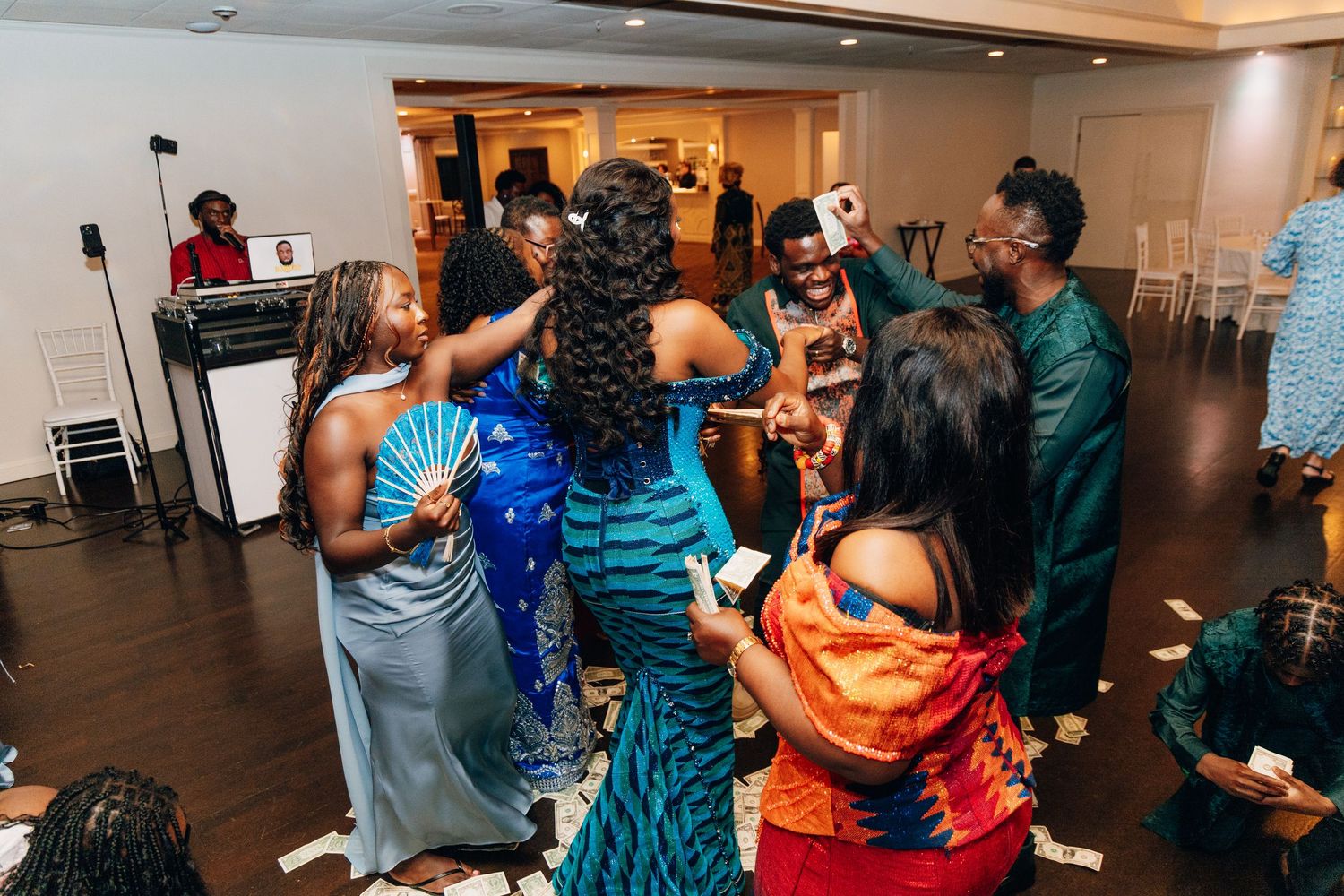 Wedding guests in colorful African attire celebrate and dance together at a lively reception party.