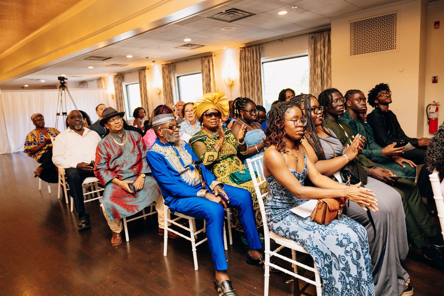 Guests in colorful African attire seated at an indoor wedding ceremony.