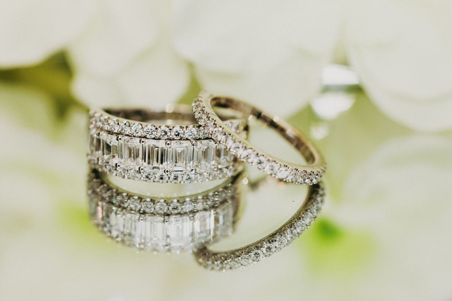 Elegant diamond wedding ring set with baguette and round stones in white gold displayed on white flowers.