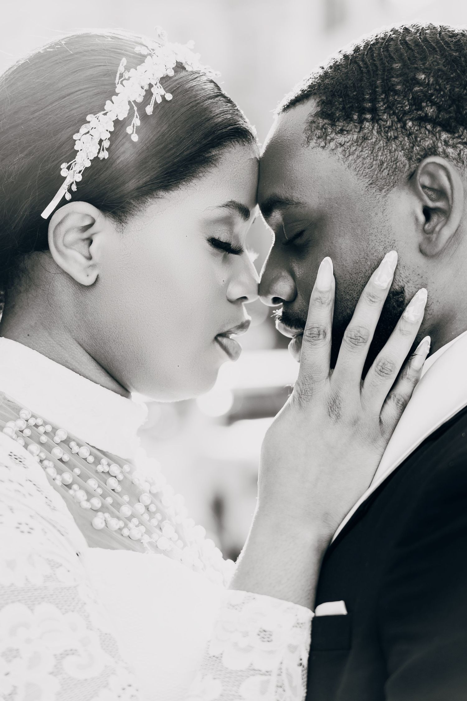 Black and white wedding photo of bride and groom sharing an intimate moment, foreheads touching, bride wearing lace dress.