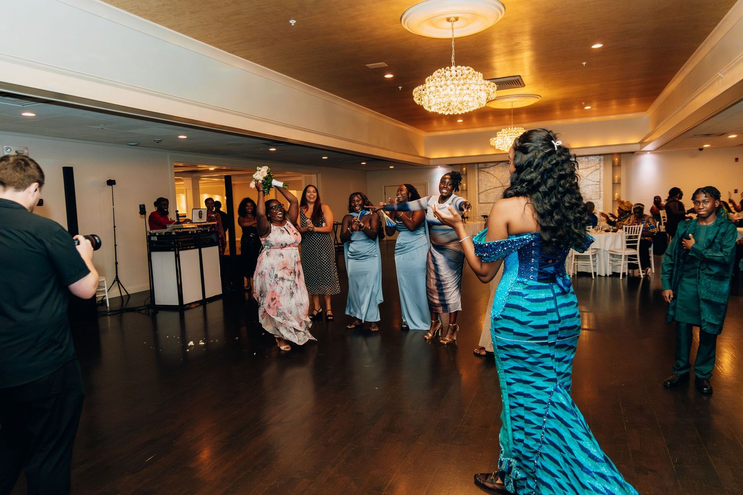 Bride in a blue mermaid gown prepares to toss the bouquet to a group of excited wedding guests.