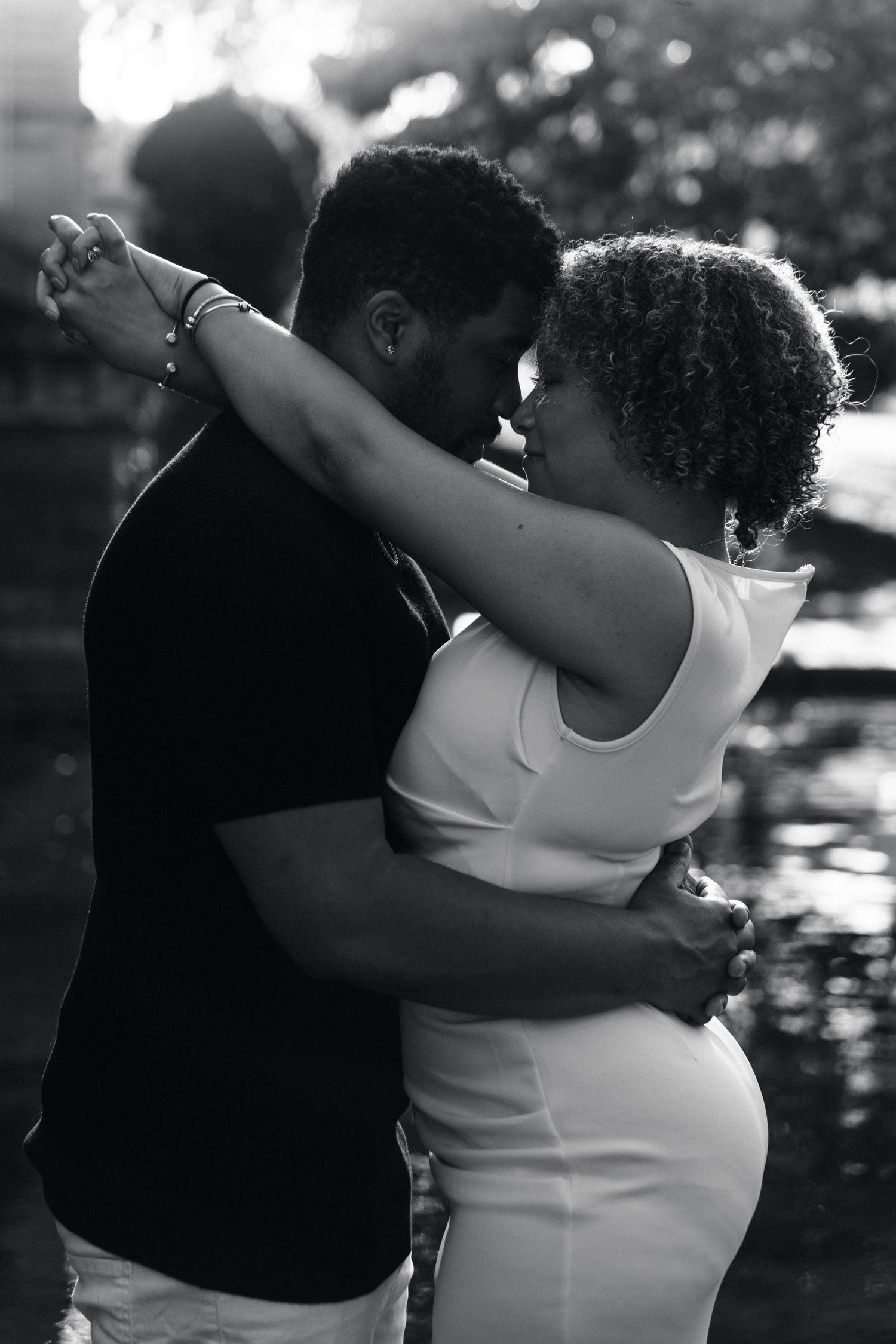 Black and white photo of a couple embracing and sharing a tender moment outdoors.