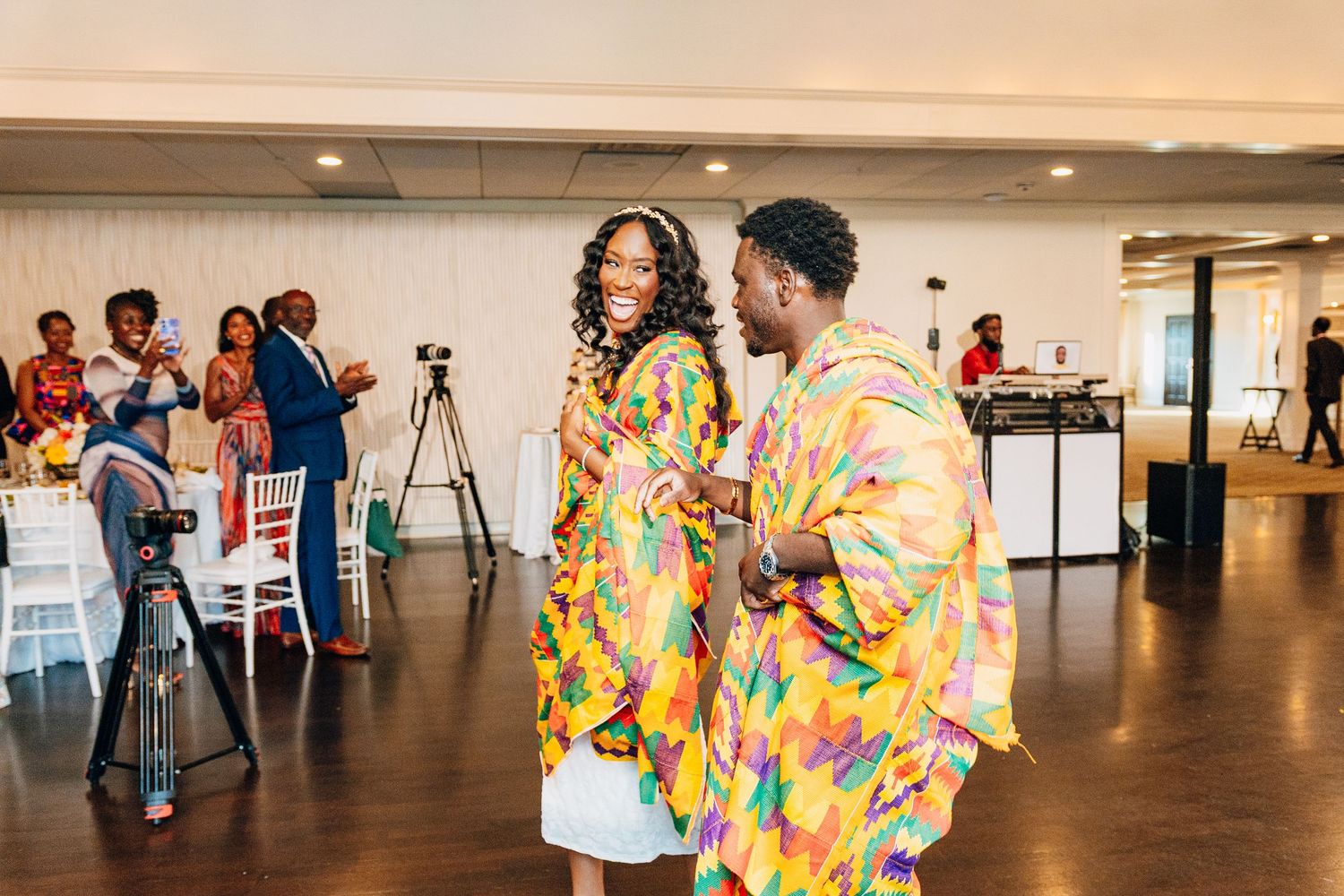 Couple dancing in vibrant colorful traditional African attire at a wedding reception celebration.