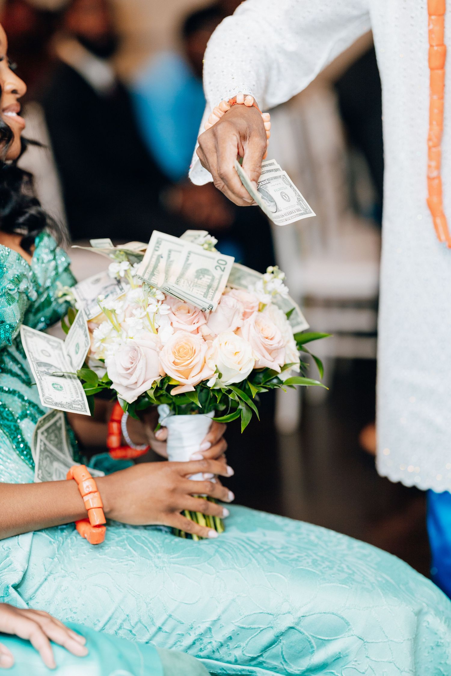Dollar bills placed in bridal bouquet of pink roses during African wedding money dance.
