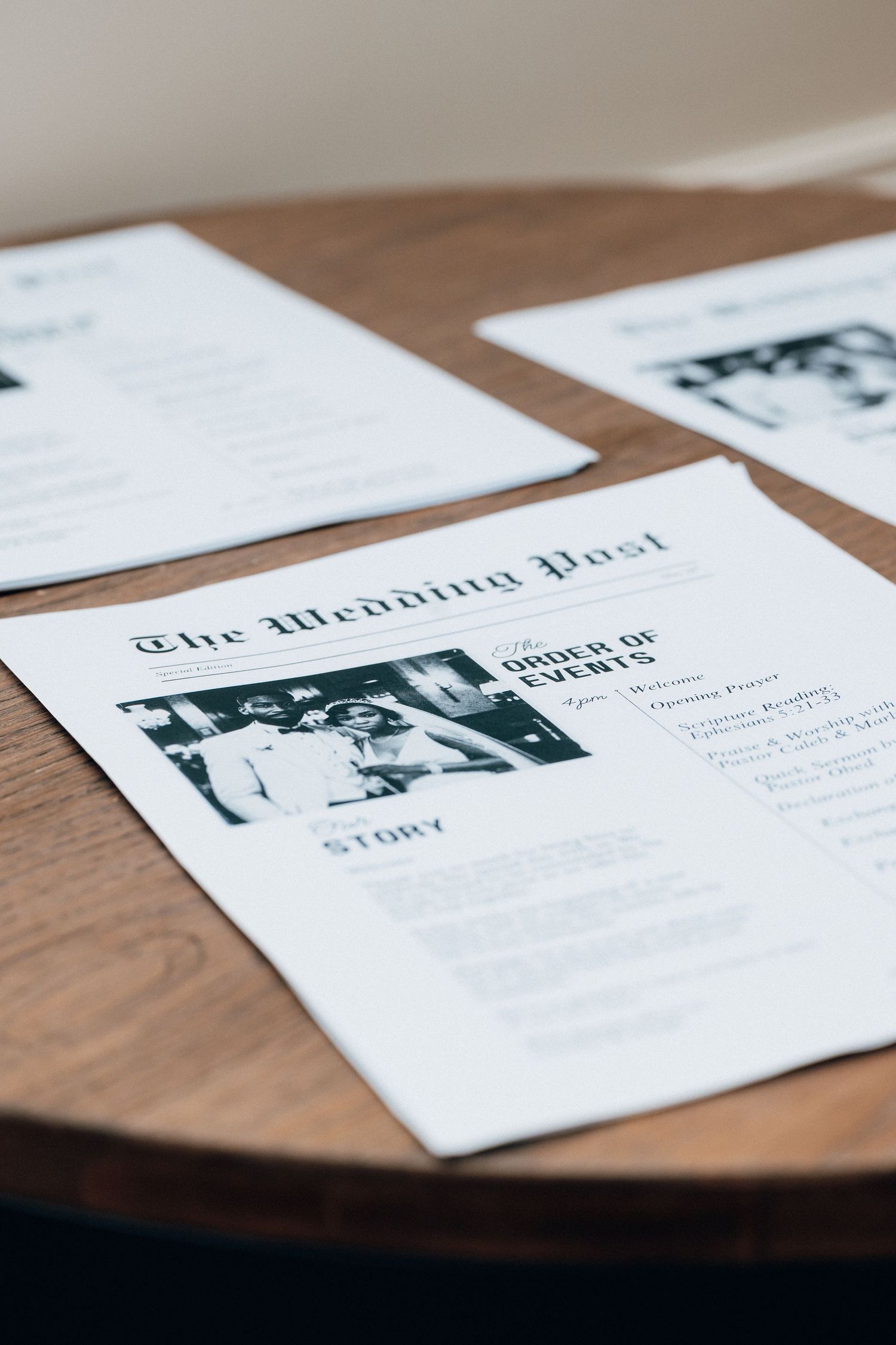 Wedding newspaper programs titled The Wedding Post with order of events displayed on a wooden table.