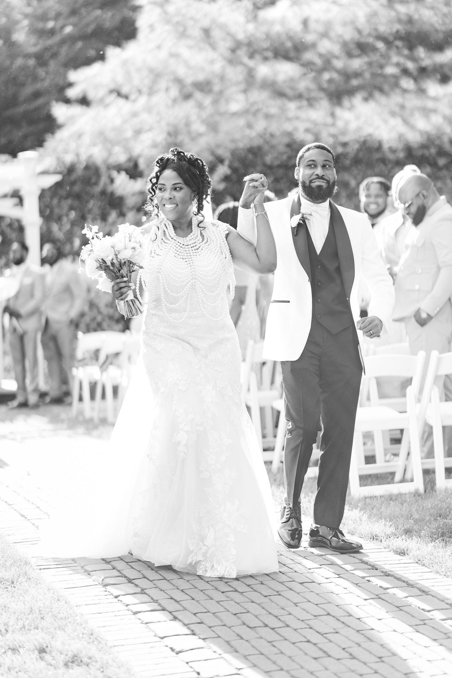 Joyful newlyweds celebrate recessional in black and white photo at outdoor wedding ceremony.