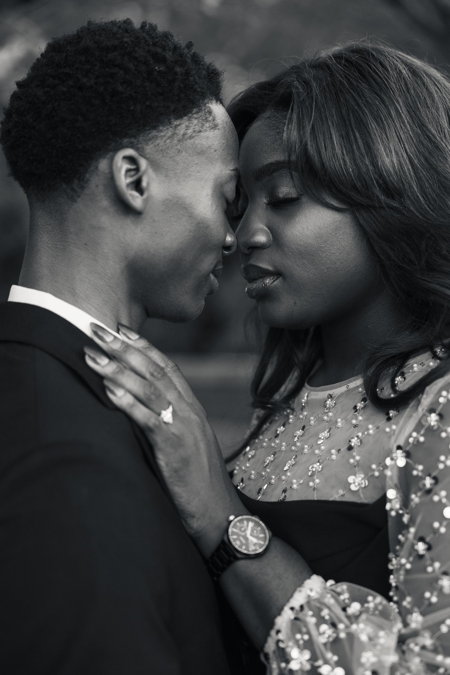 Black and white photo of a romantic couple sharing an intimate moment, the woman placing her hand on the mans chest.