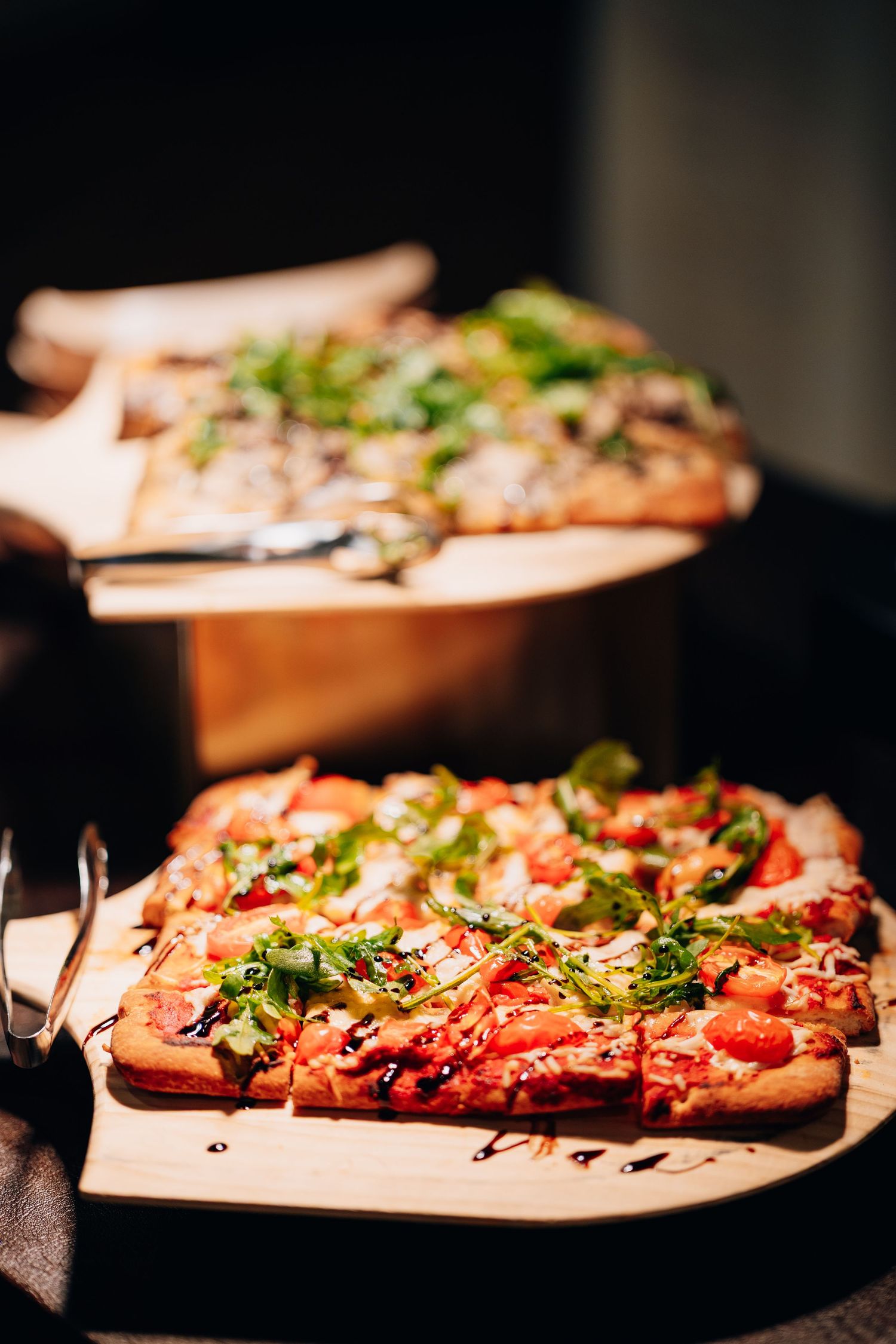 Gourmet flatbread pizza topped with fresh arugula and balsamic glaze served on wooden boards.