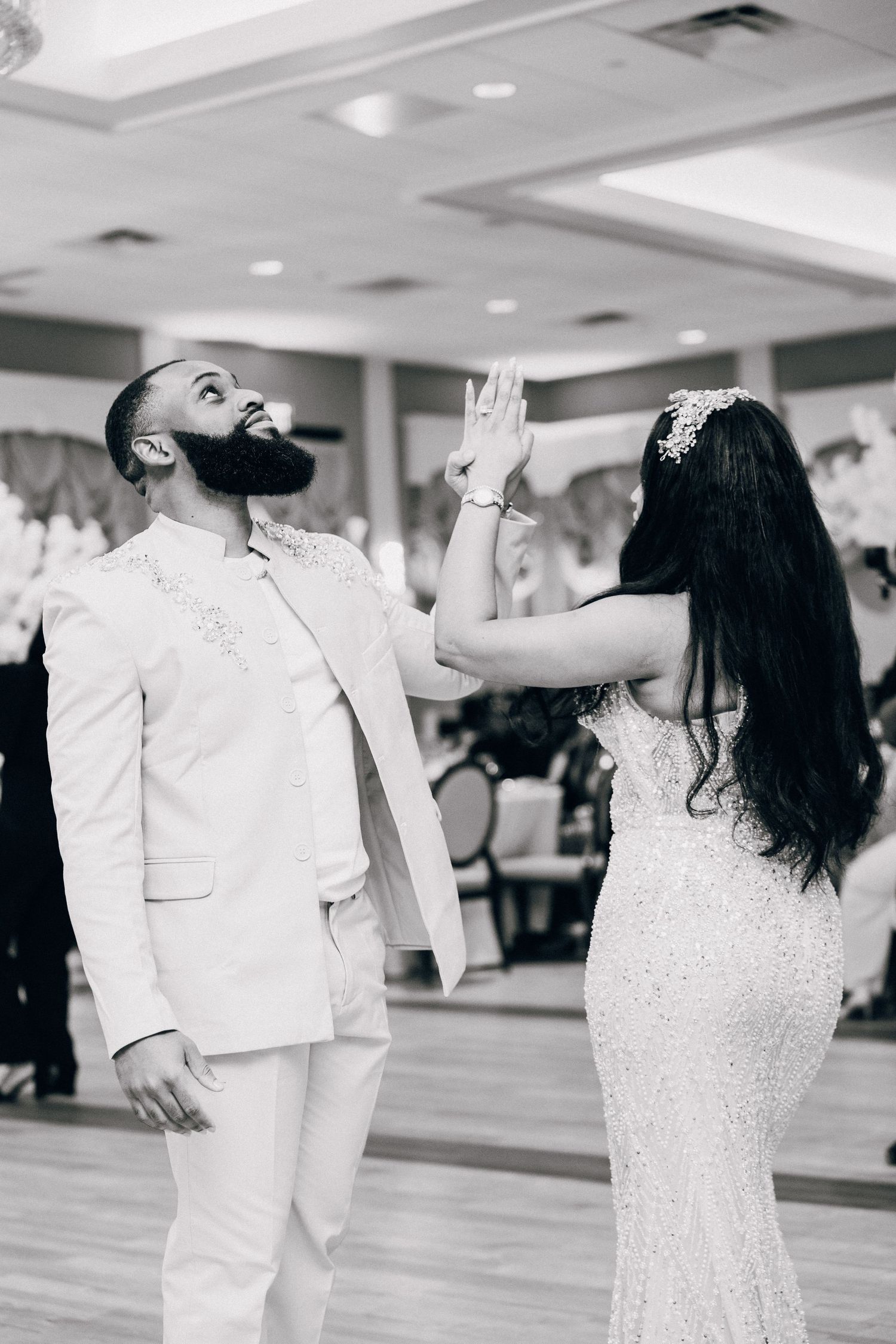 Black and white photo of bride and groom sharing a romantic high-five moment during their first dance.
