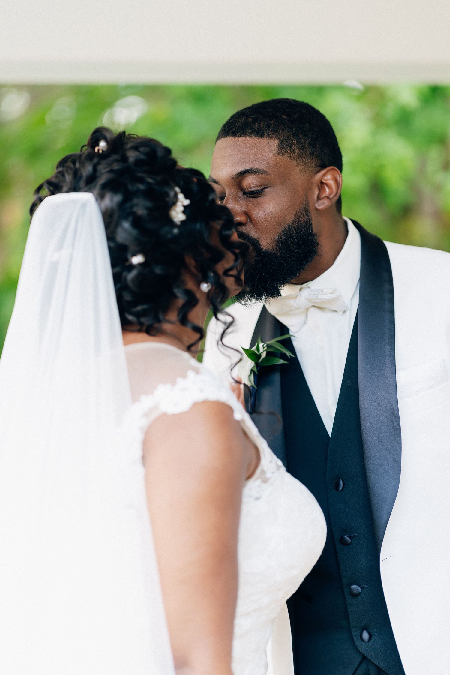 A Black bride and groom share their first kiss at the altar during an outdoor wedding ceremony.