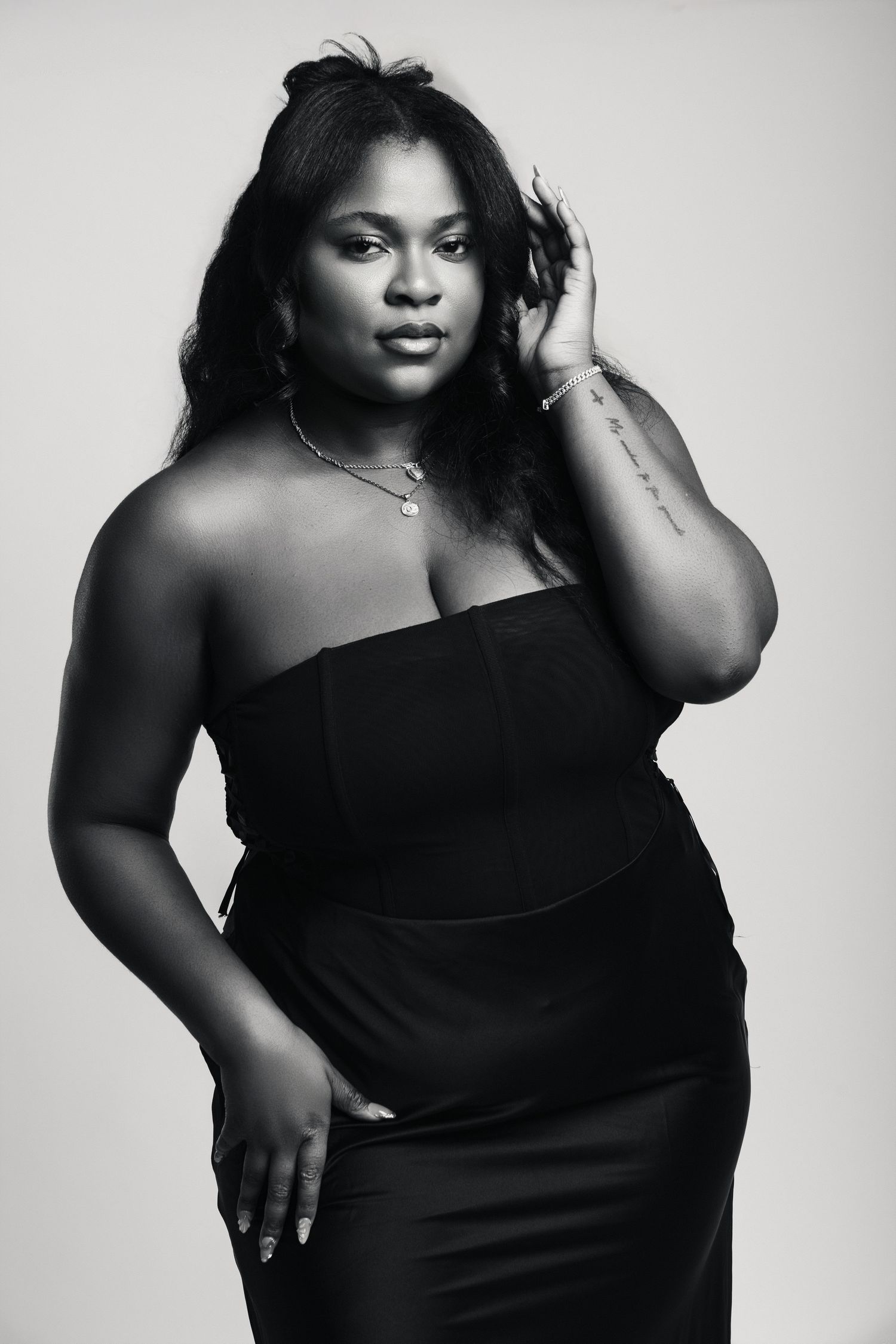 Black and white portrait of a woman in a strapless black dress posing confidently.