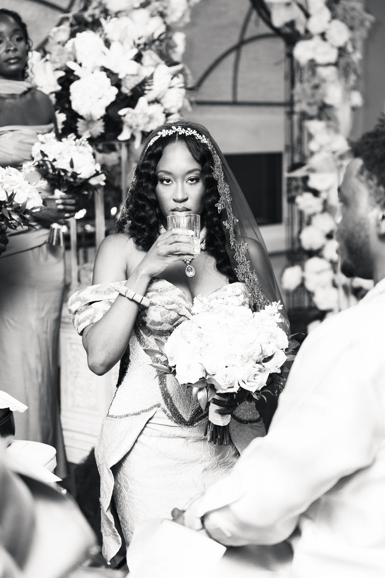 Black and white photo of bride drinking from cup during wedding ceremony.