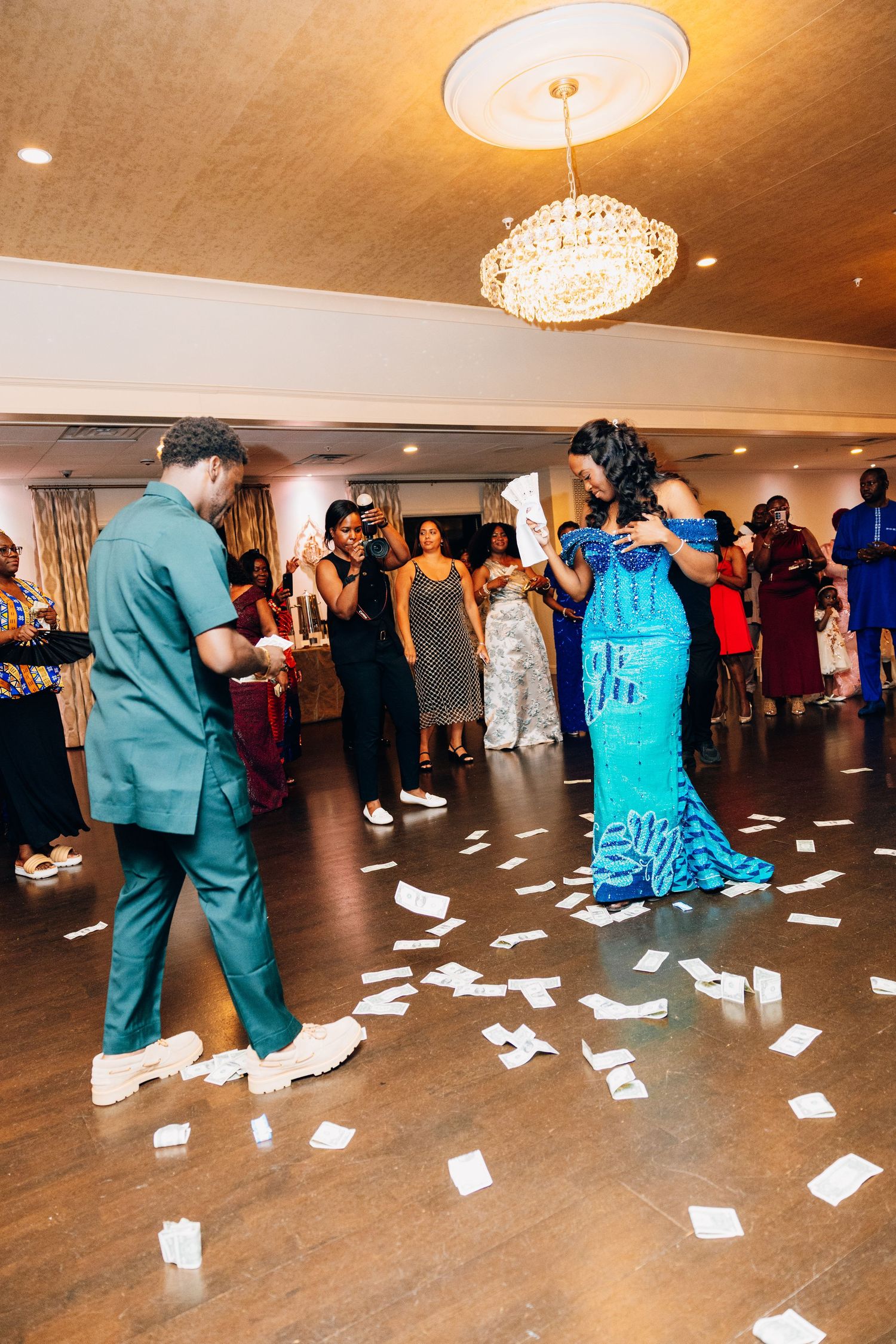 Couple dancing as money covers floor at vibrant African wedding reception celebration.