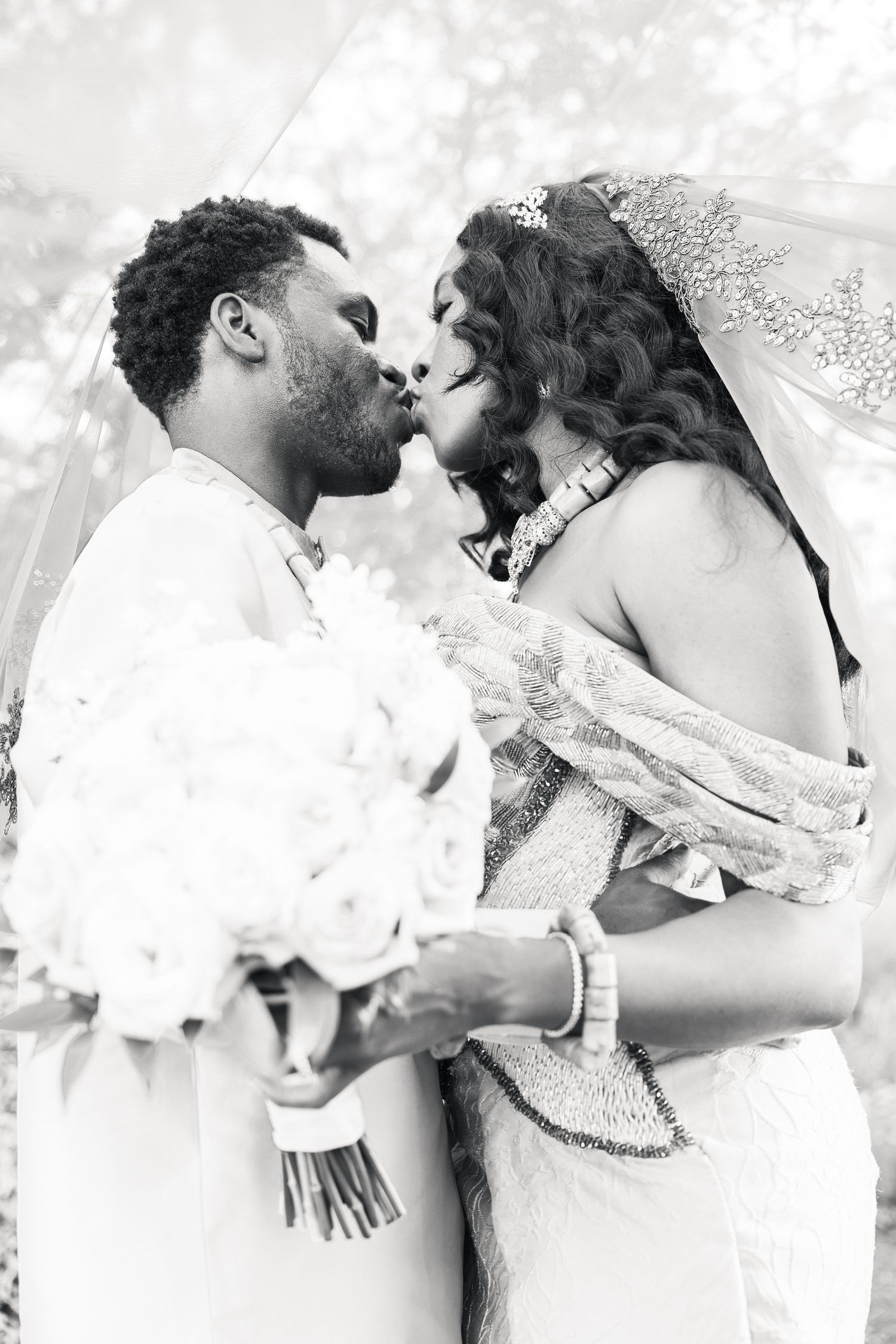 Black and white photo of bride and groom kissing at wedding.