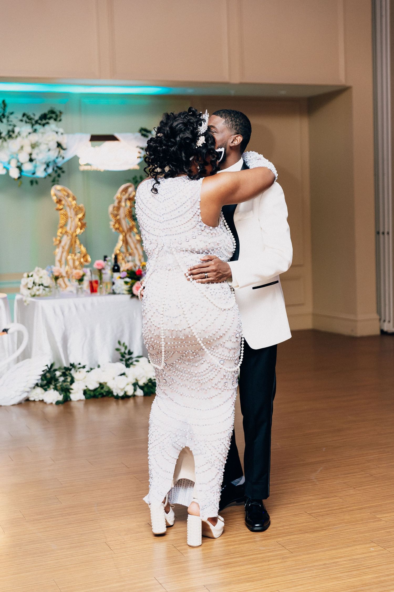 Bride and groom sharing their first dance, bride wearing a pearl-embellished white gown at wedding reception.