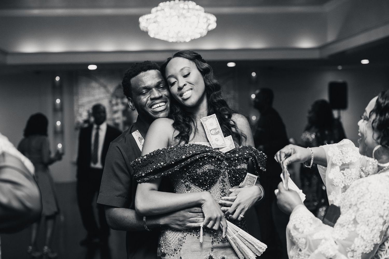 Black and white photo of a couple sharing a joyful embrace on the dance floor at a wedding reception.