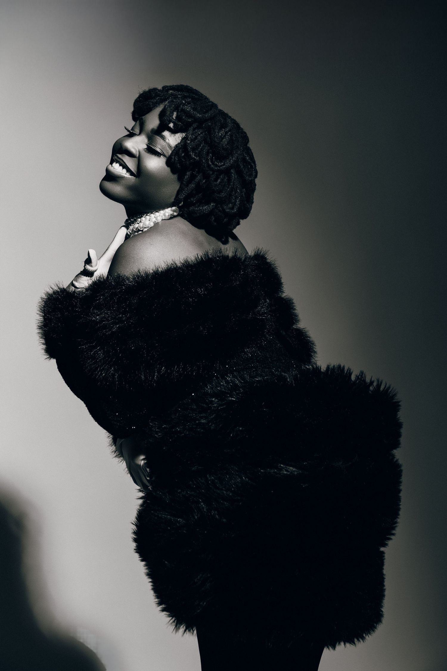 Black and white portrait of a woman in a fur coat looking up, vintage glamour style photography.