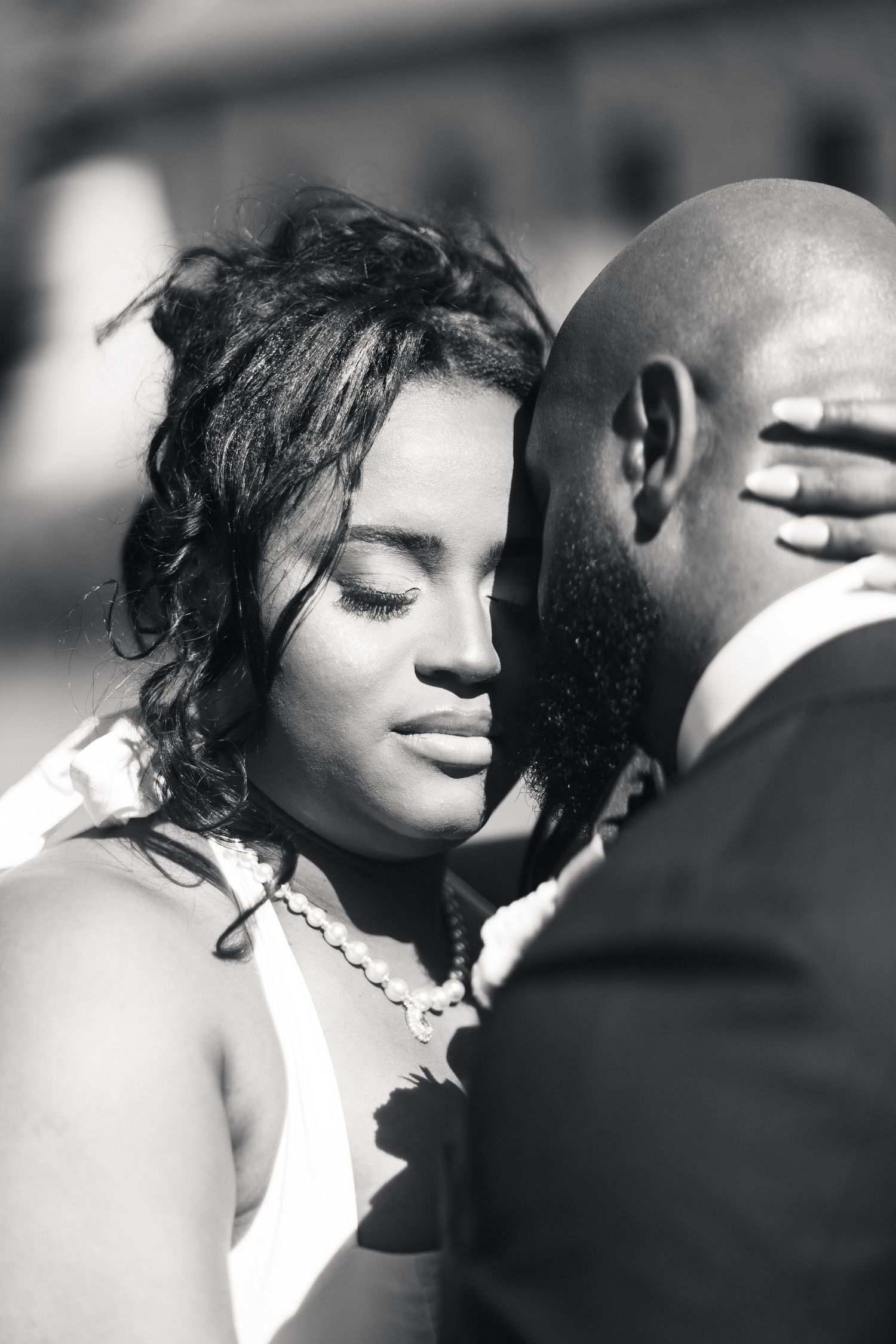 Black and white close-up of bride tenderly embracing groom on their wedding day.