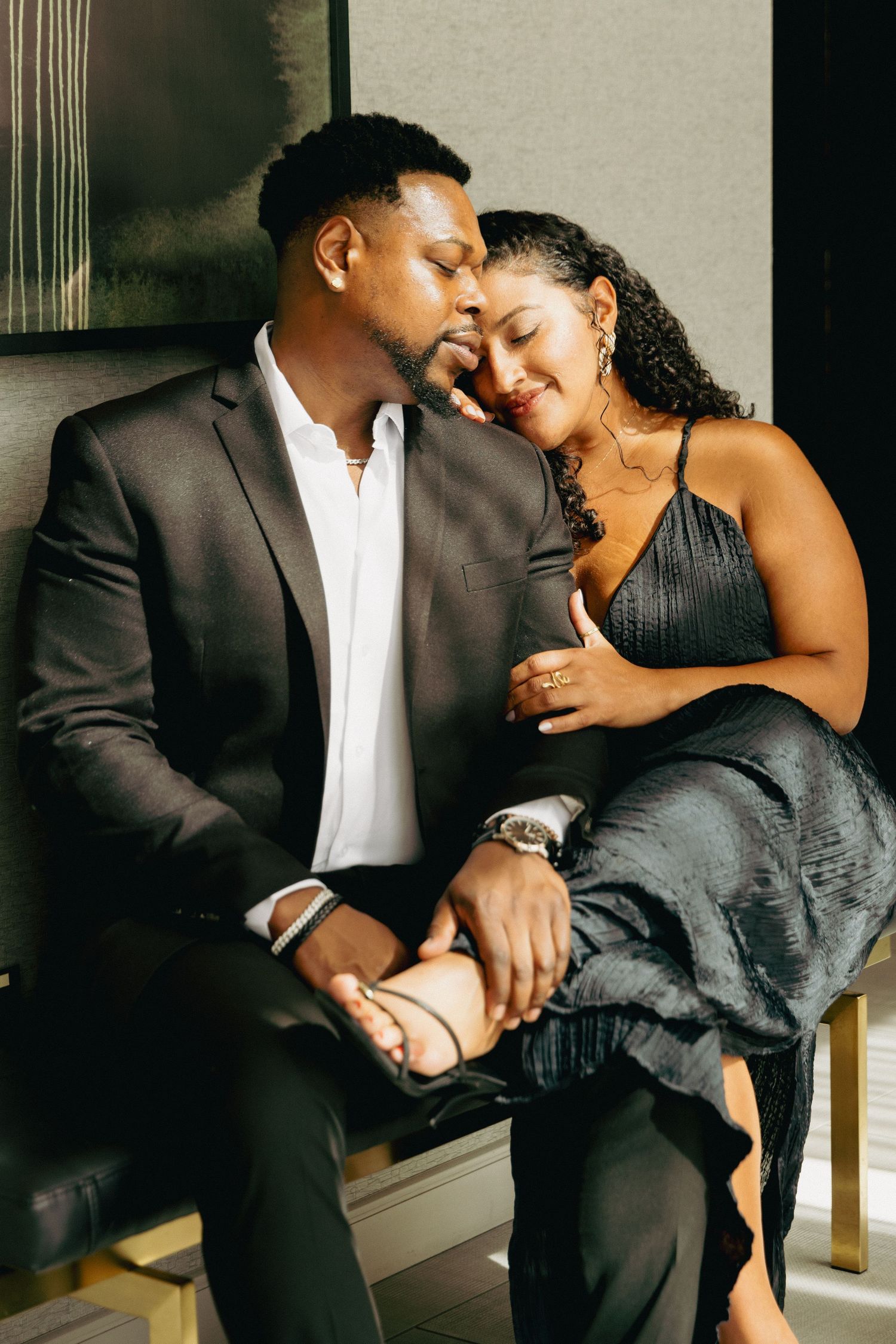 Elegant couple in formal attire sharing a romantic moment, man in suit and woman in black dress holding hands.