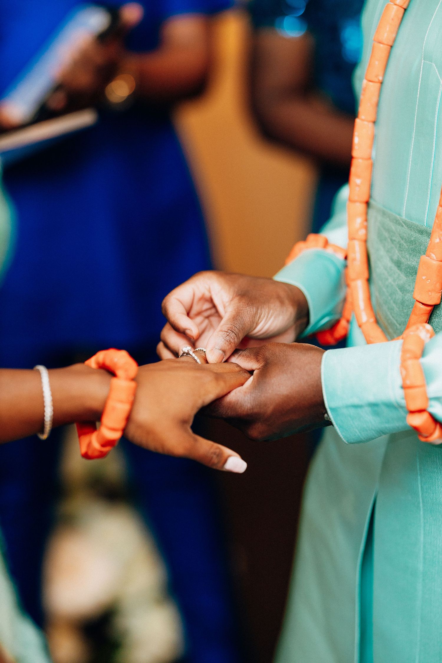Close-up of a ring exchange during a Nigerian traditional wedding ceremony with orange coral beads.