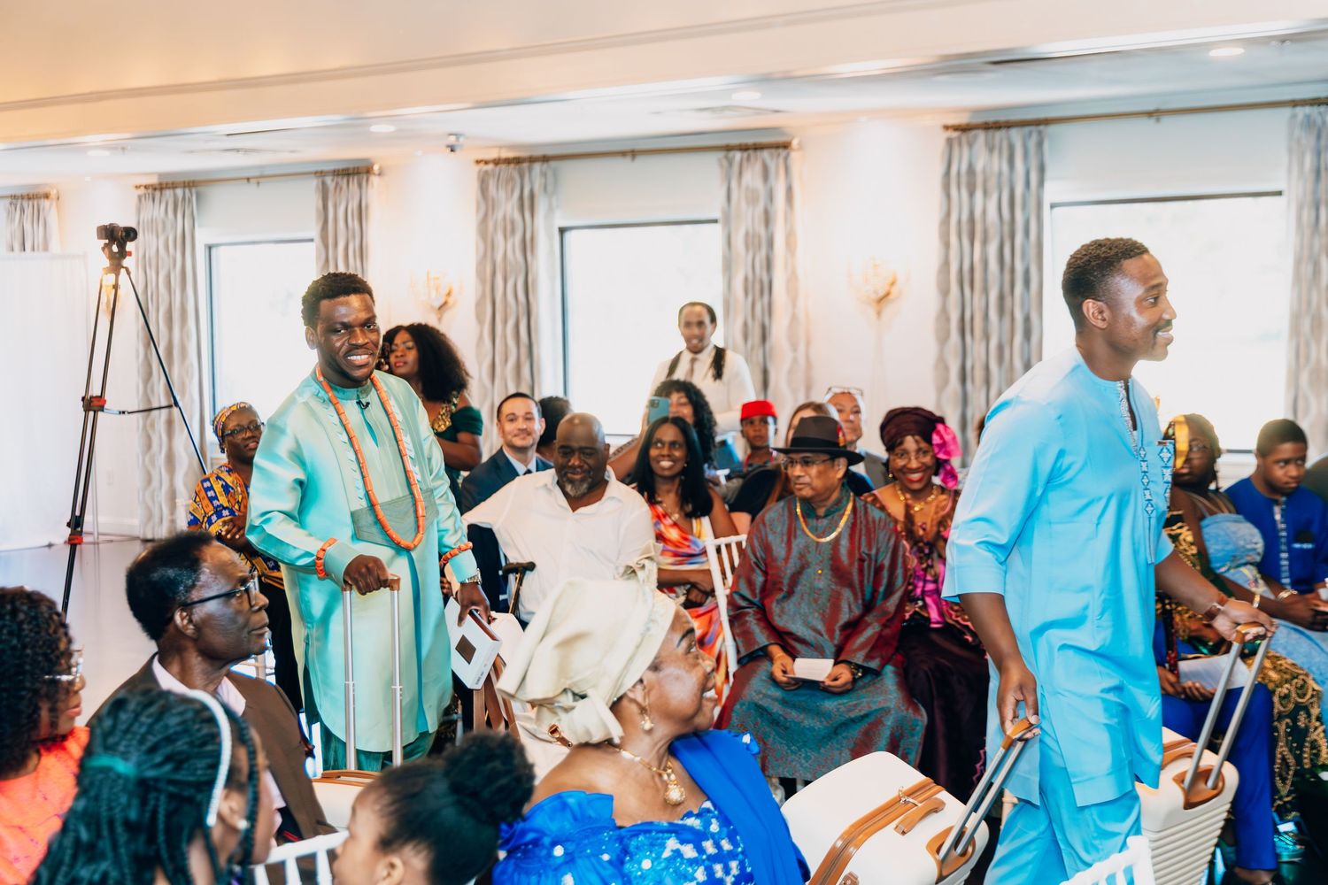Guests in vibrant African attire celebrate at a traditional wedding ceremony indoors.