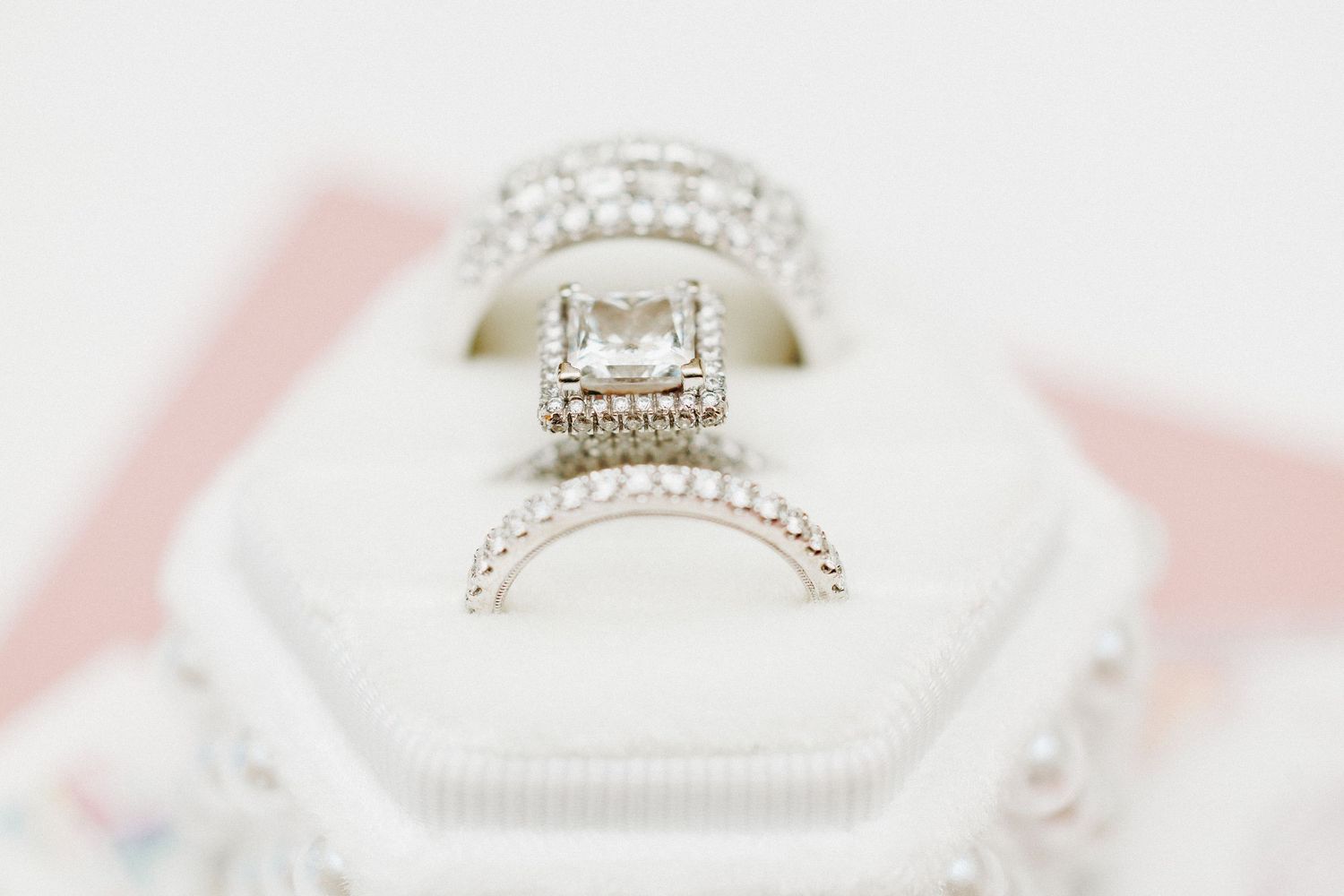 Elegant diamond engagement ring with halo setting and wedding band displayed in a white ring box.