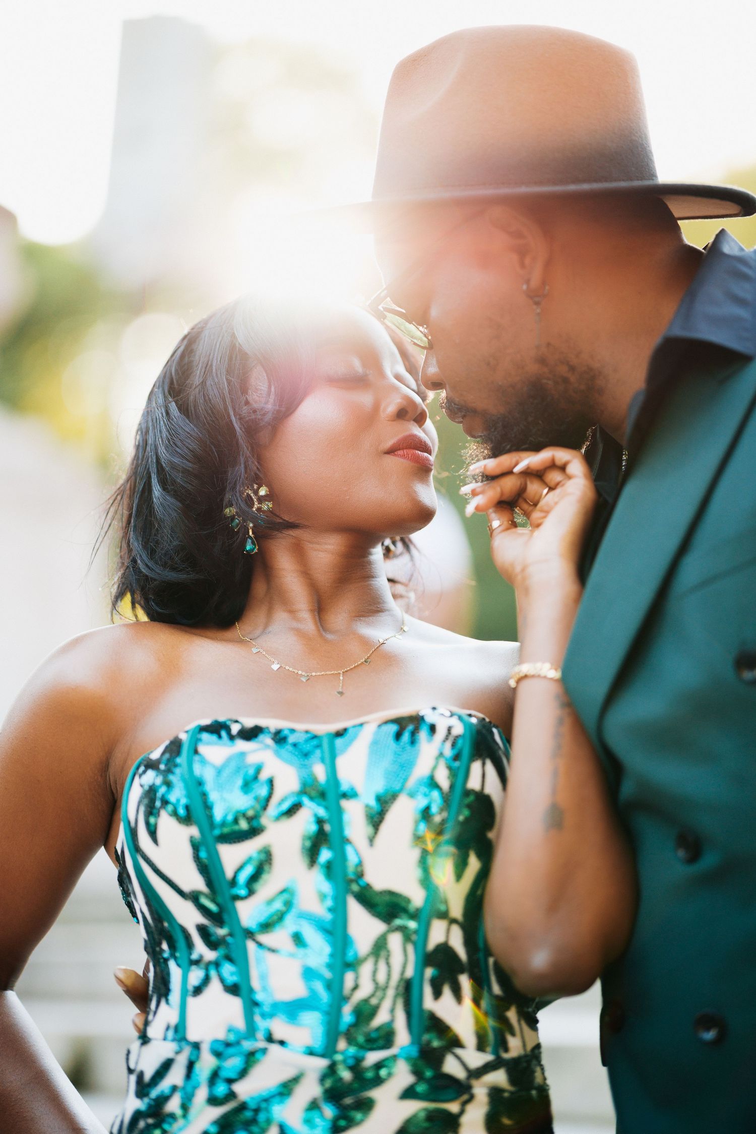 Romantic Black couple sharing intimate moment with golden sunlight backlit floral strapless dress.