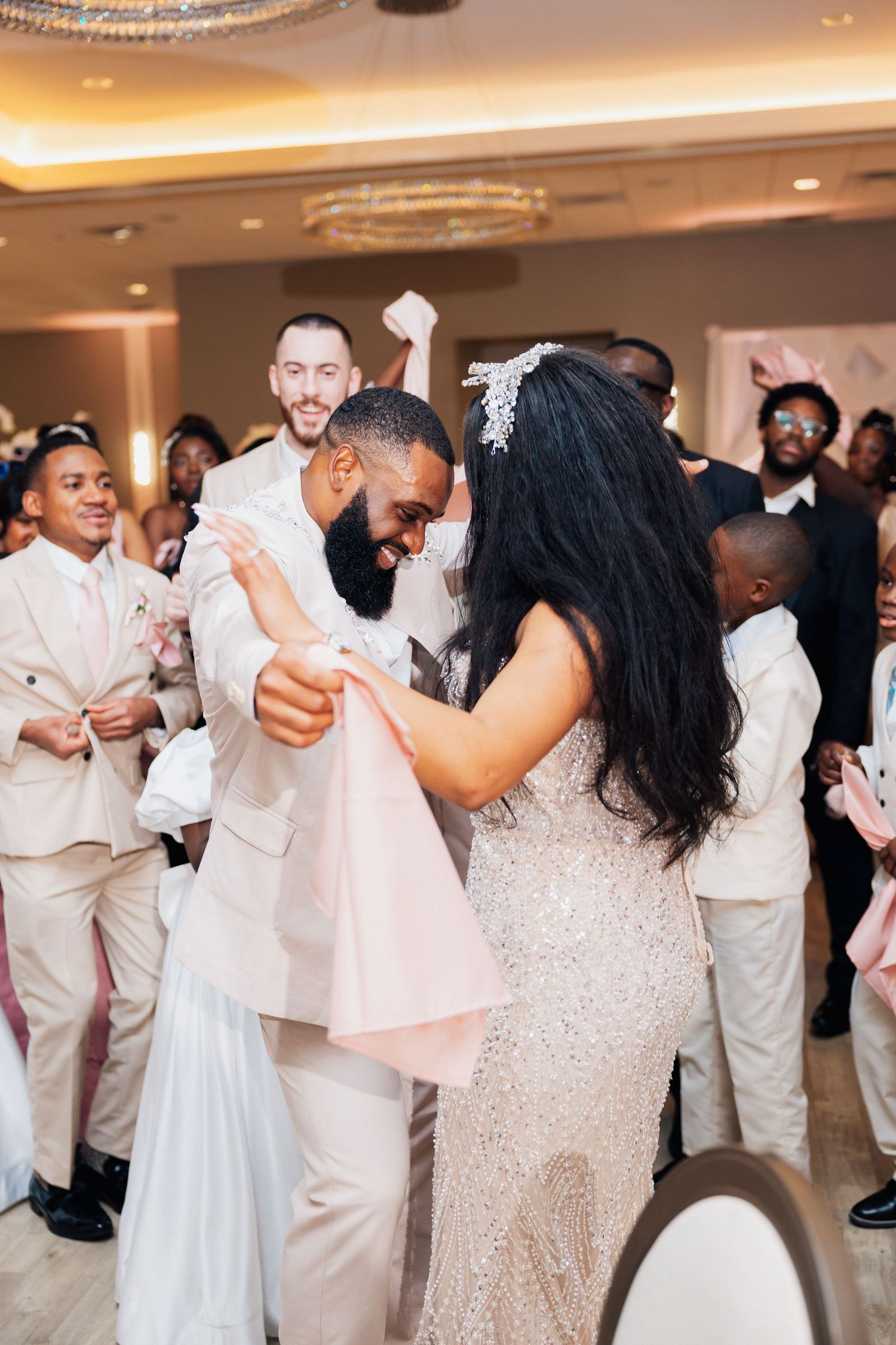 Bride and groom share first dance surrounded by joyful guests at elegant wedding reception.