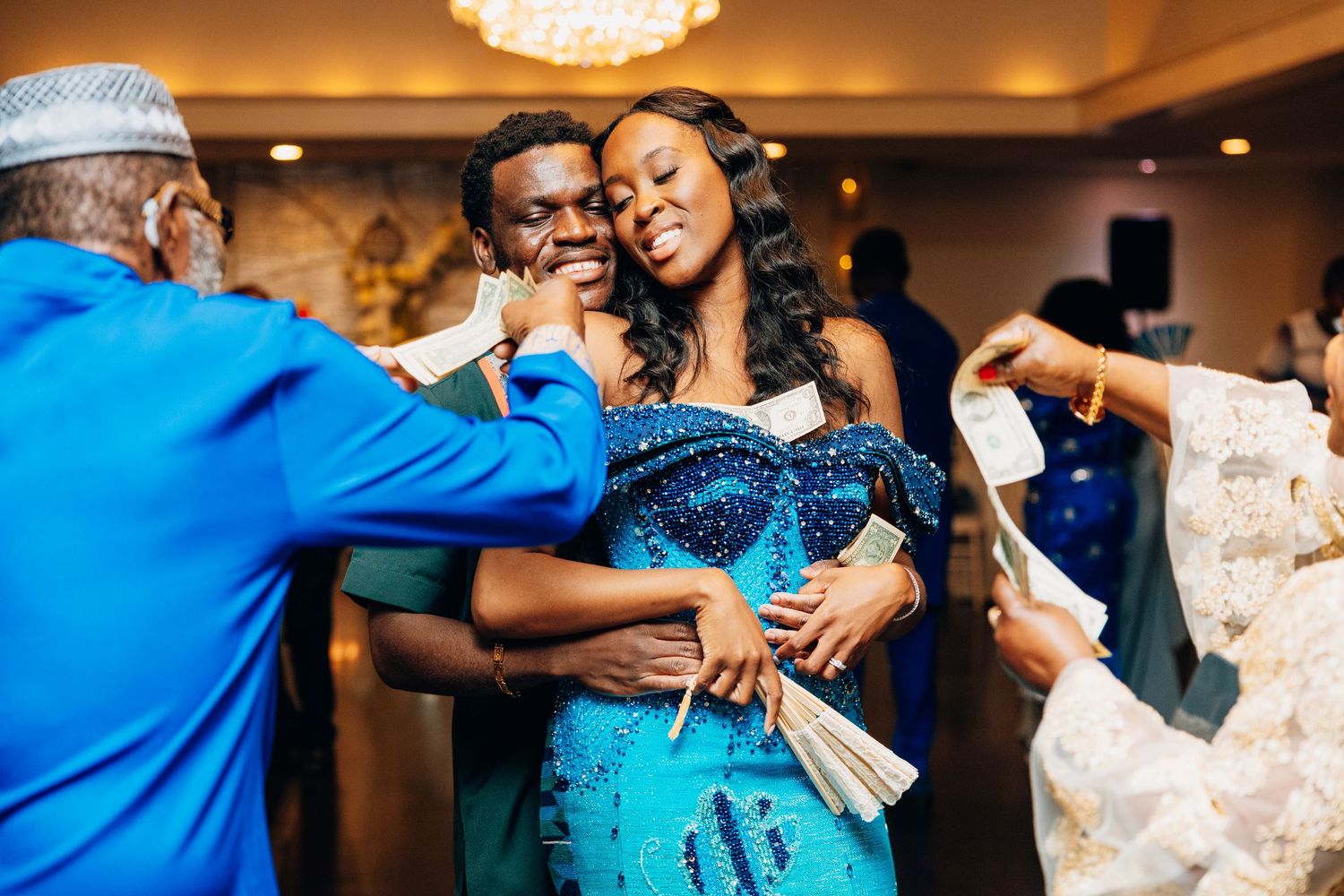 Wedding guests spraying money on couple during African traditional wedding celebration.