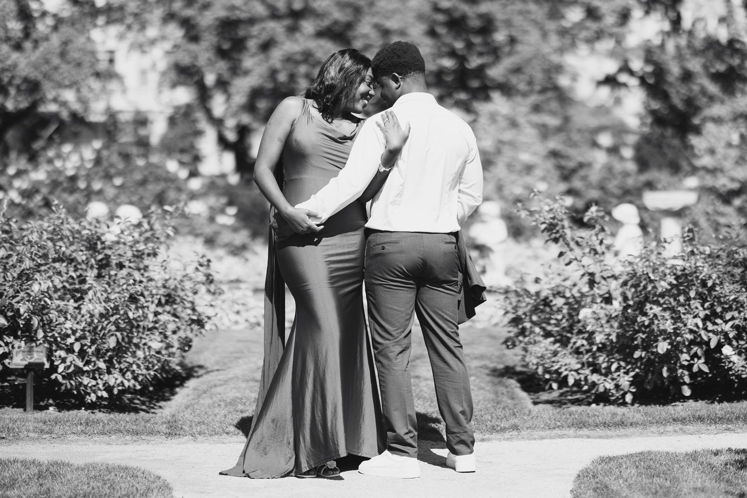 Couple embracing from behind in a garden, black and white romantic outdoor portrait photography.