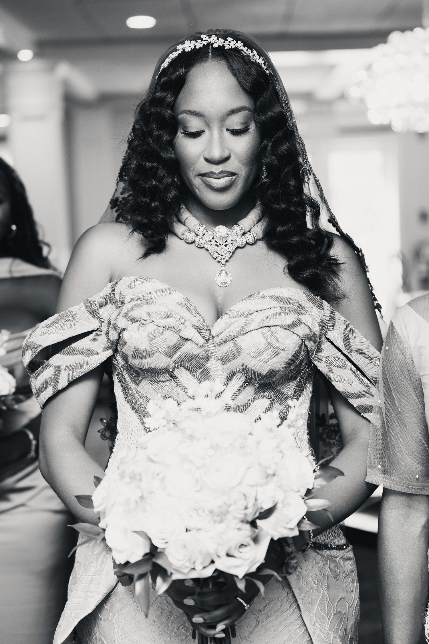 Beautiful Black bride in strapless beaded gown holding white bouquet, black and white photo.