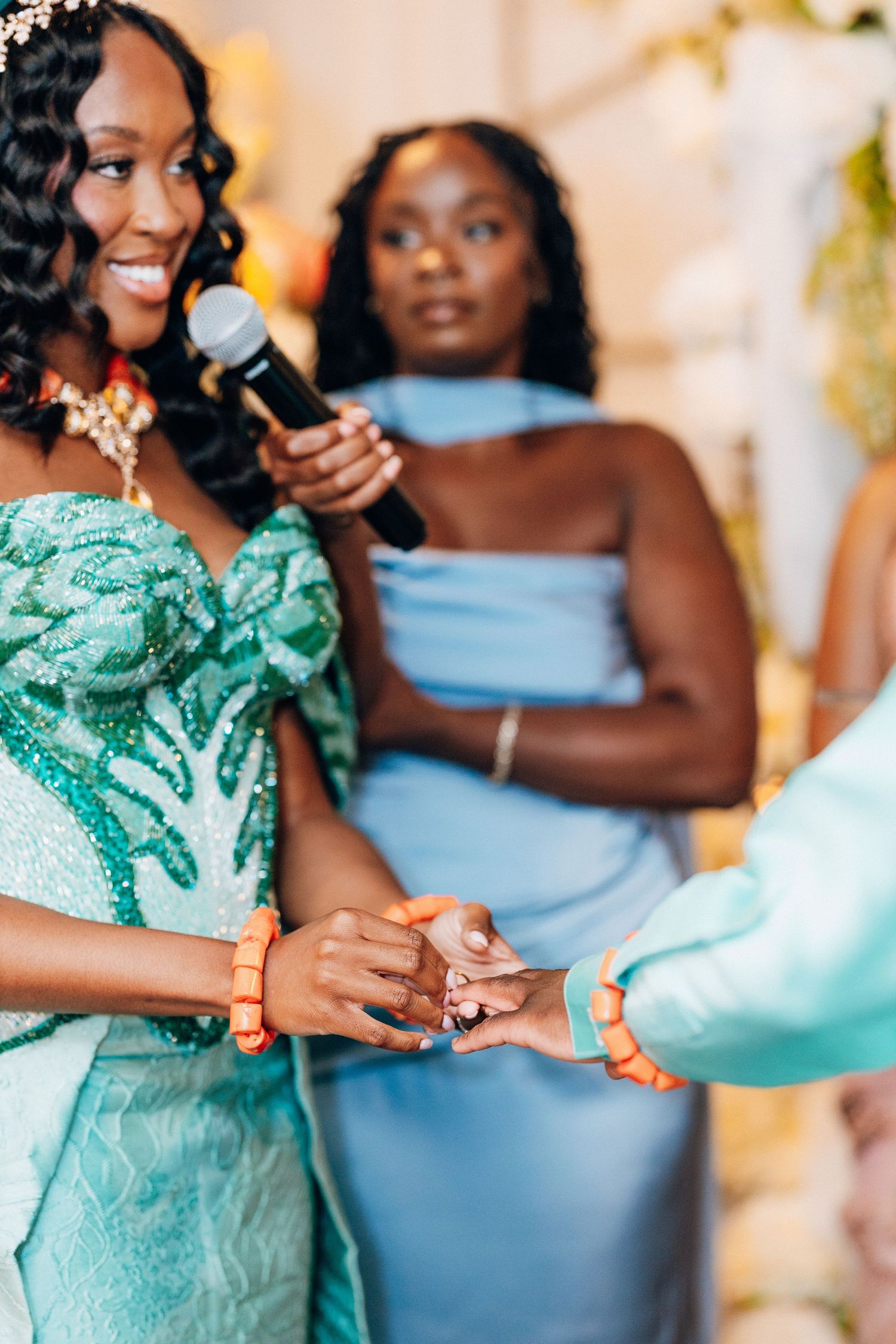 Smiling bride in teal Nigerian traditional attire exchanges rings during a joyful wedding ceremony.