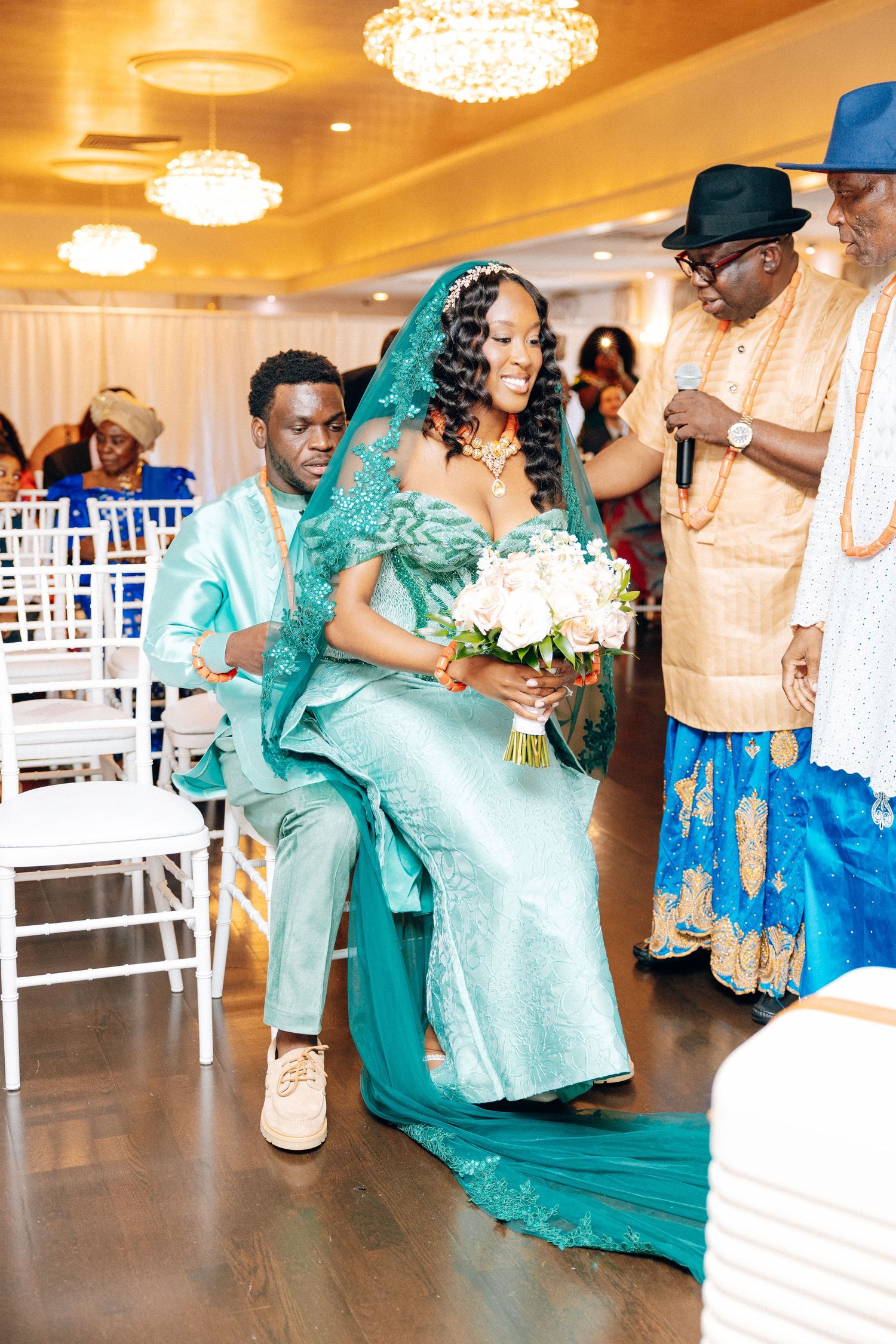 Bride and groom in matching teal outfits during African traditional wedding ceremony.