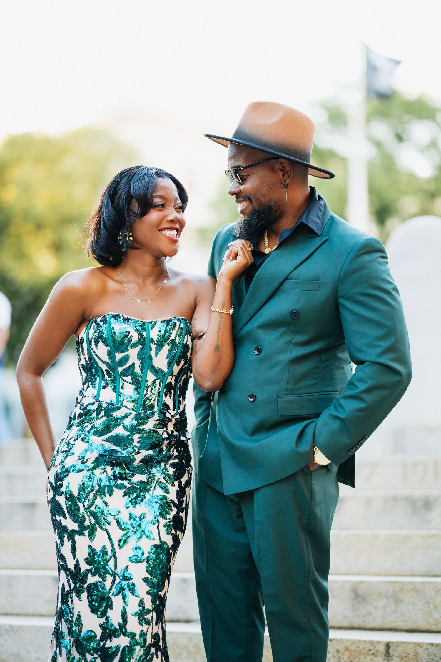Elegant Black couple in matching green outfits smiling at each other outdoors.