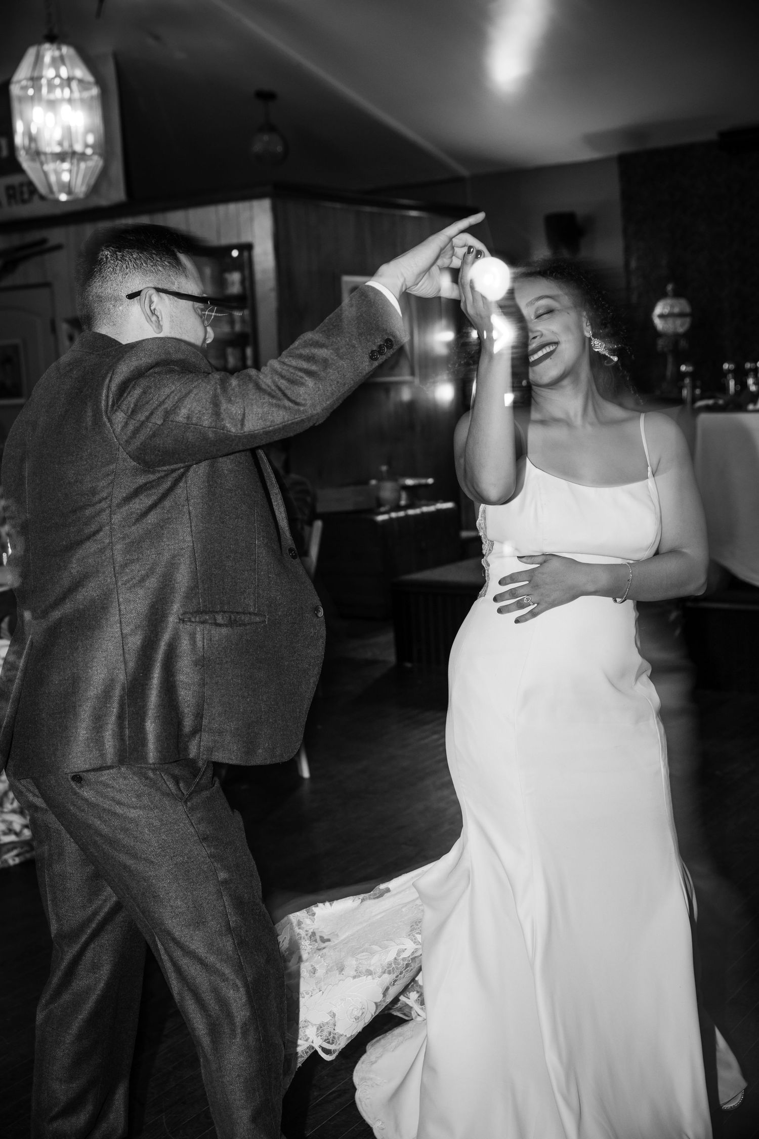 Black and white photo of a bride and groom sharing a joyful dance at their wedding reception.