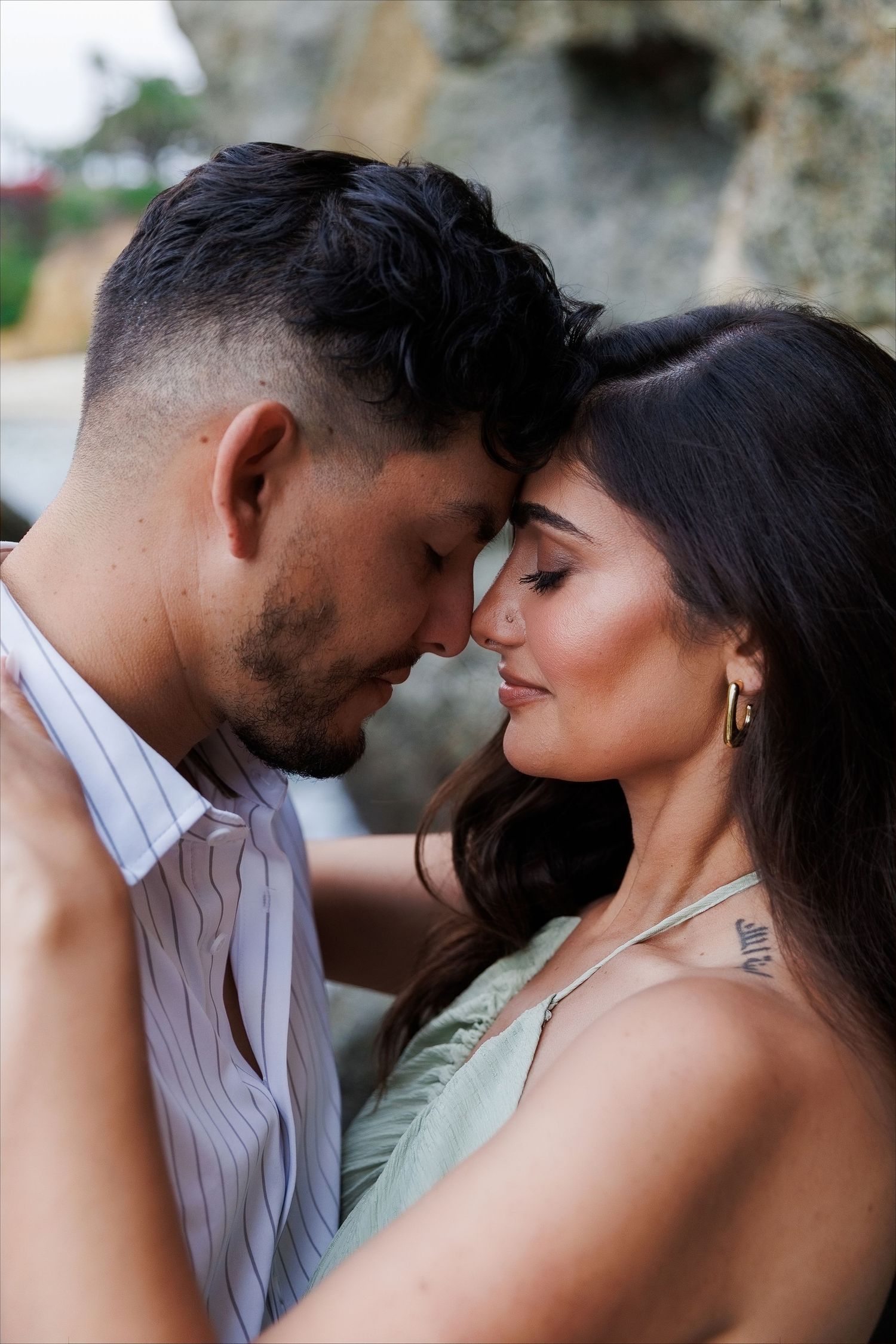Romantic couple sharing an intimate moment, touching foreheads with eyes closed in a tender embrace outdoors.