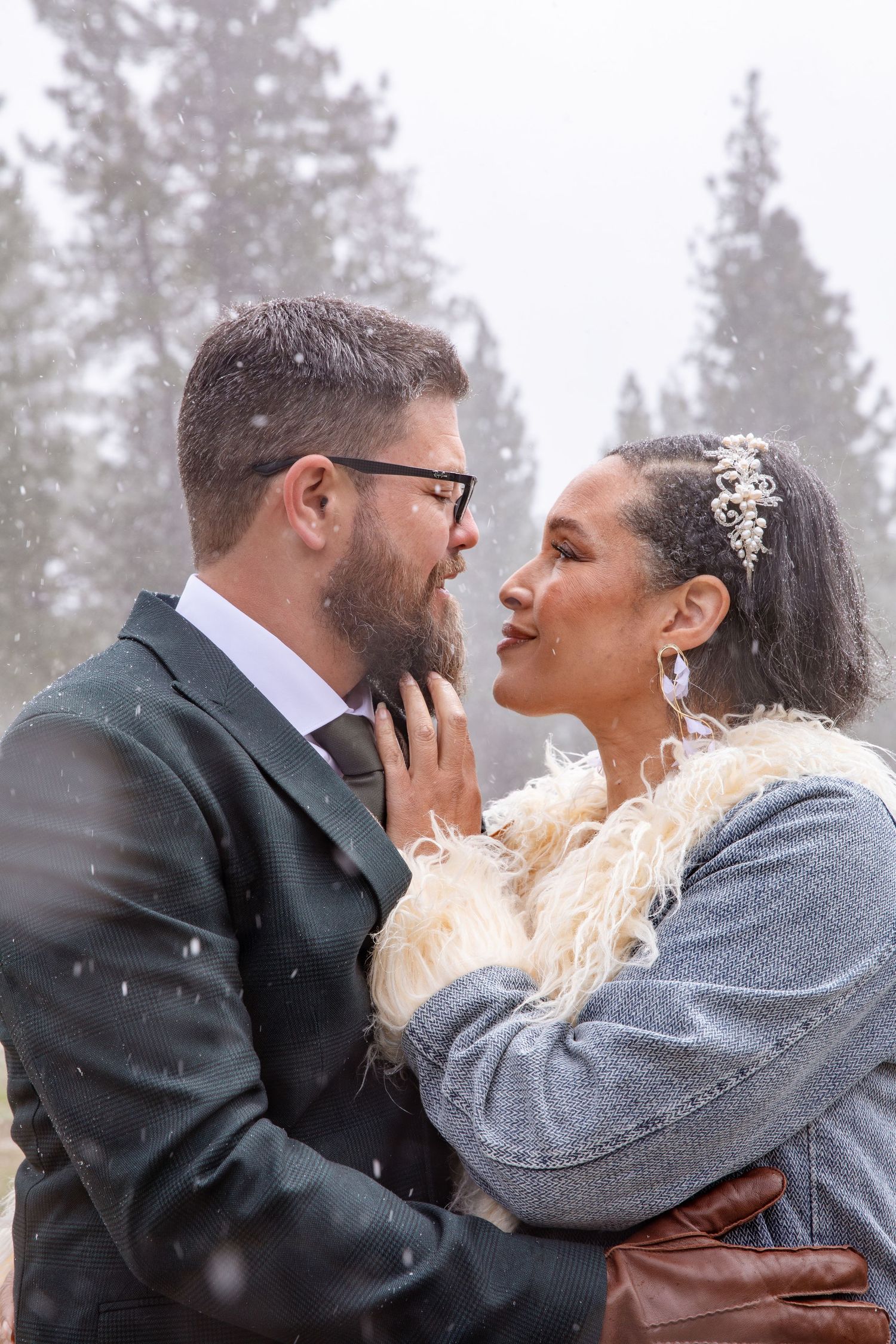 A romantic winter moment captured between a couple in warm clothing with snowflakes falling.