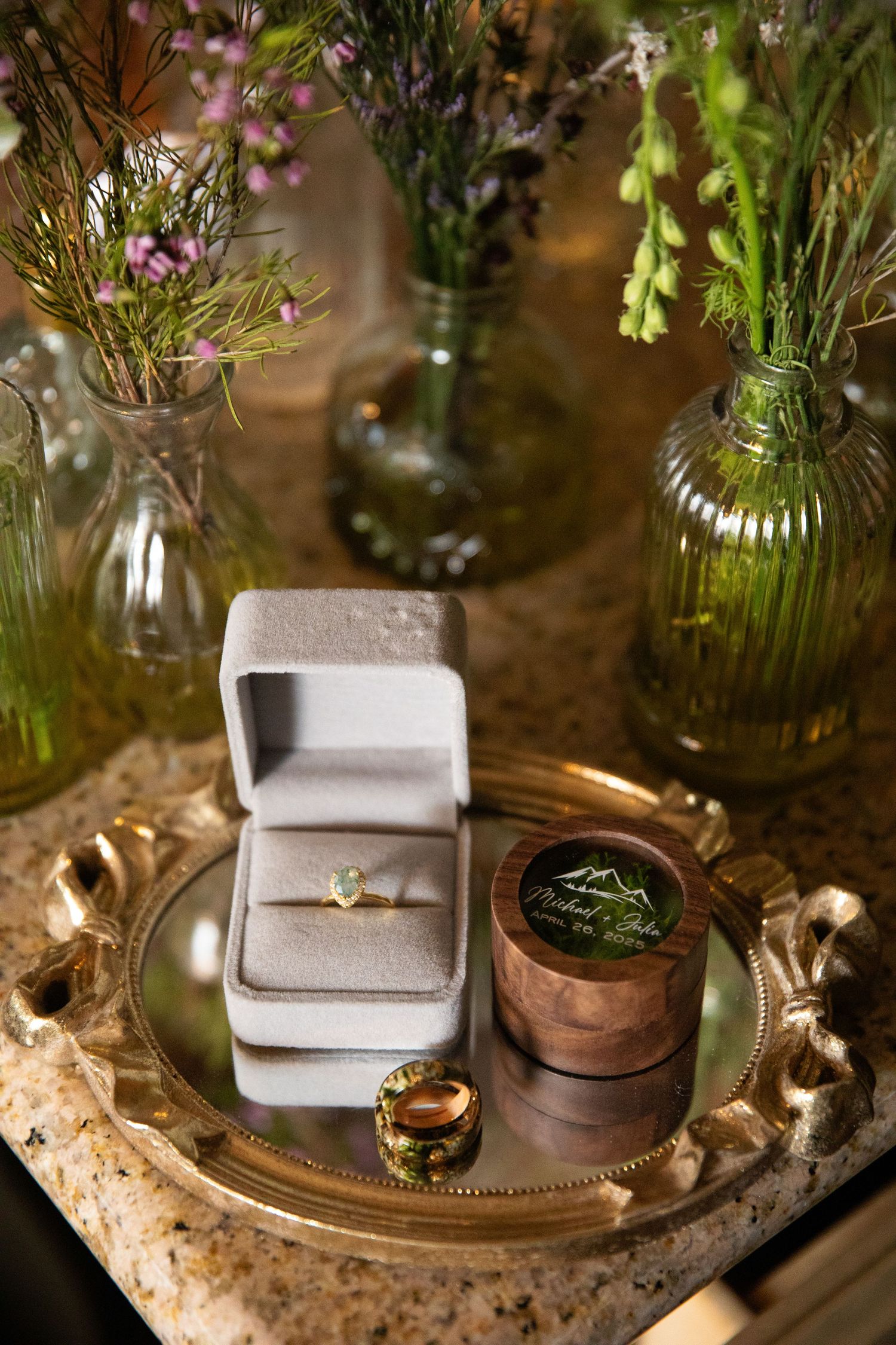 Wedding ring boxes and delicate floral arrangements displayed on decorative trays.