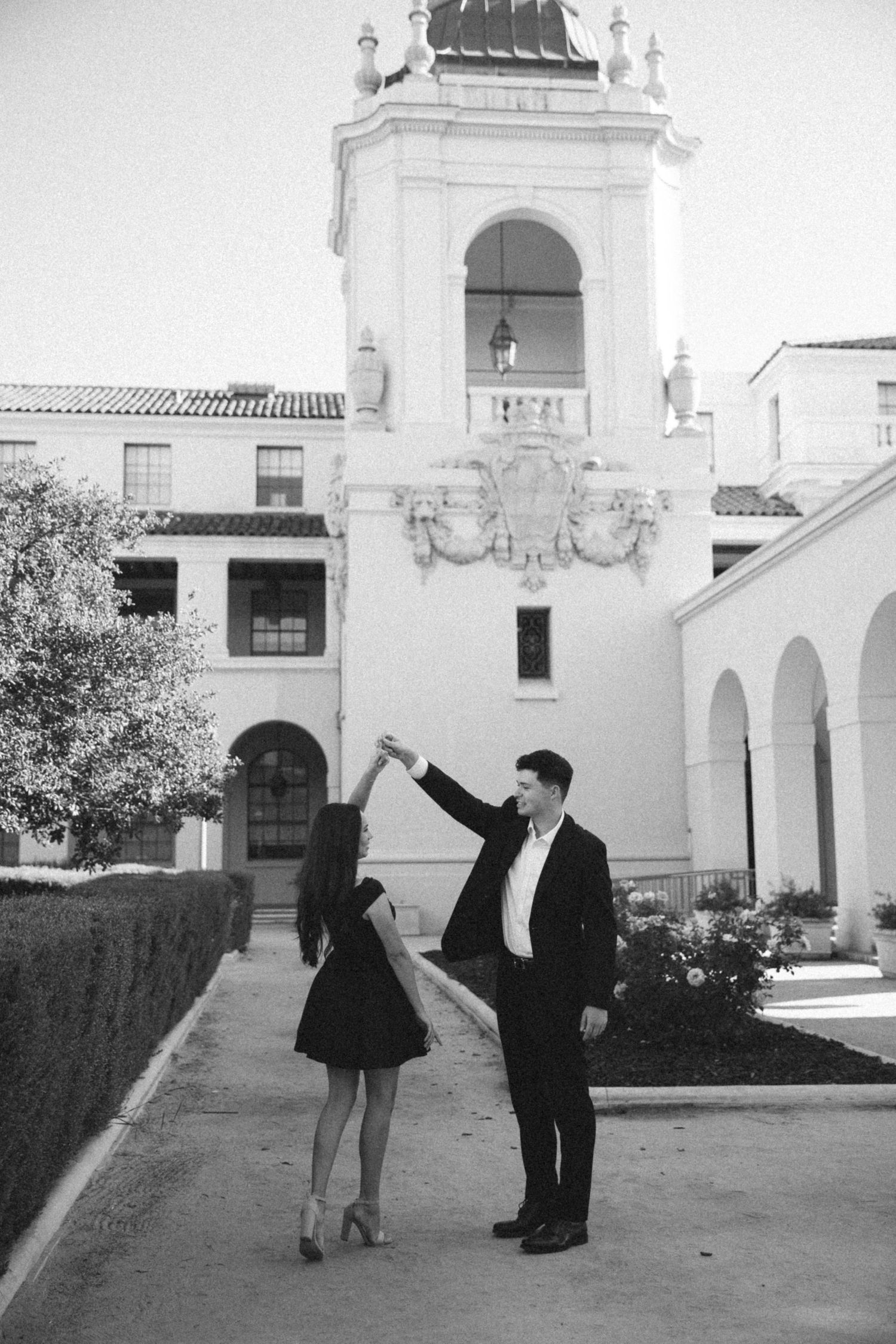Black and white engagement photos taken at a historic mission with Spanish architecture.
