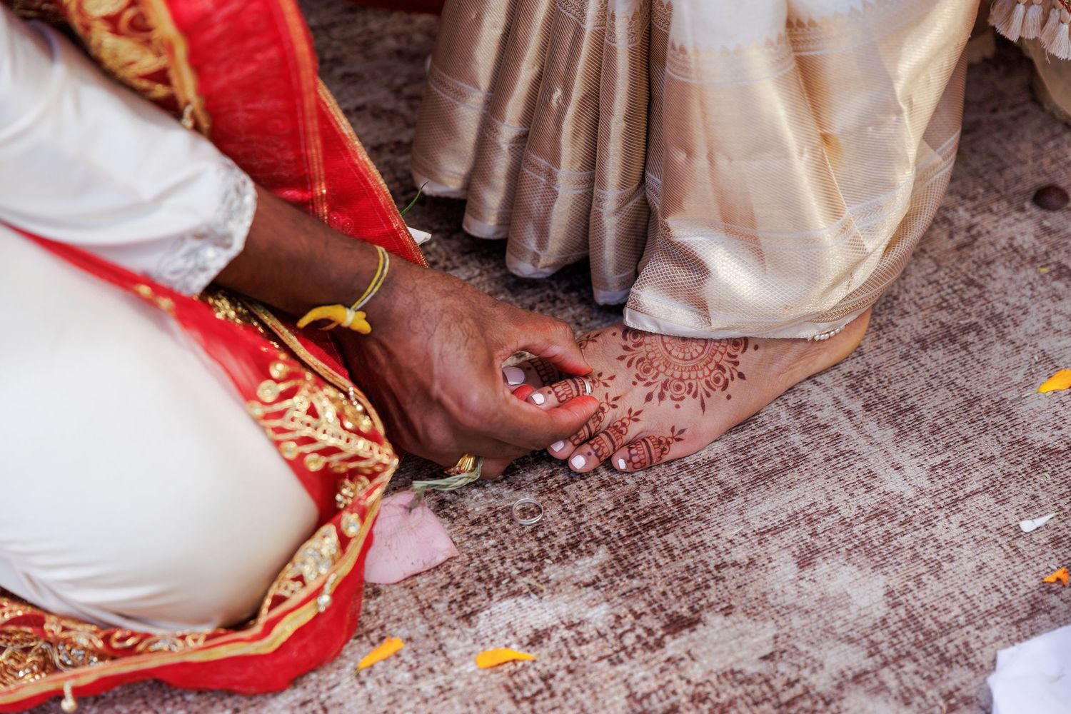 Close-up of henna-adorned feet during a traditional Indian wedding ceremony ritual.