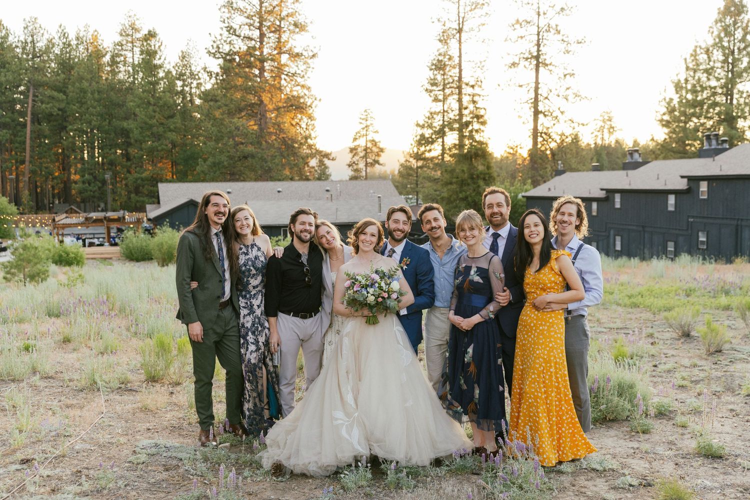 Wedding party and guests gather for group photos in a natural outdoor setting.