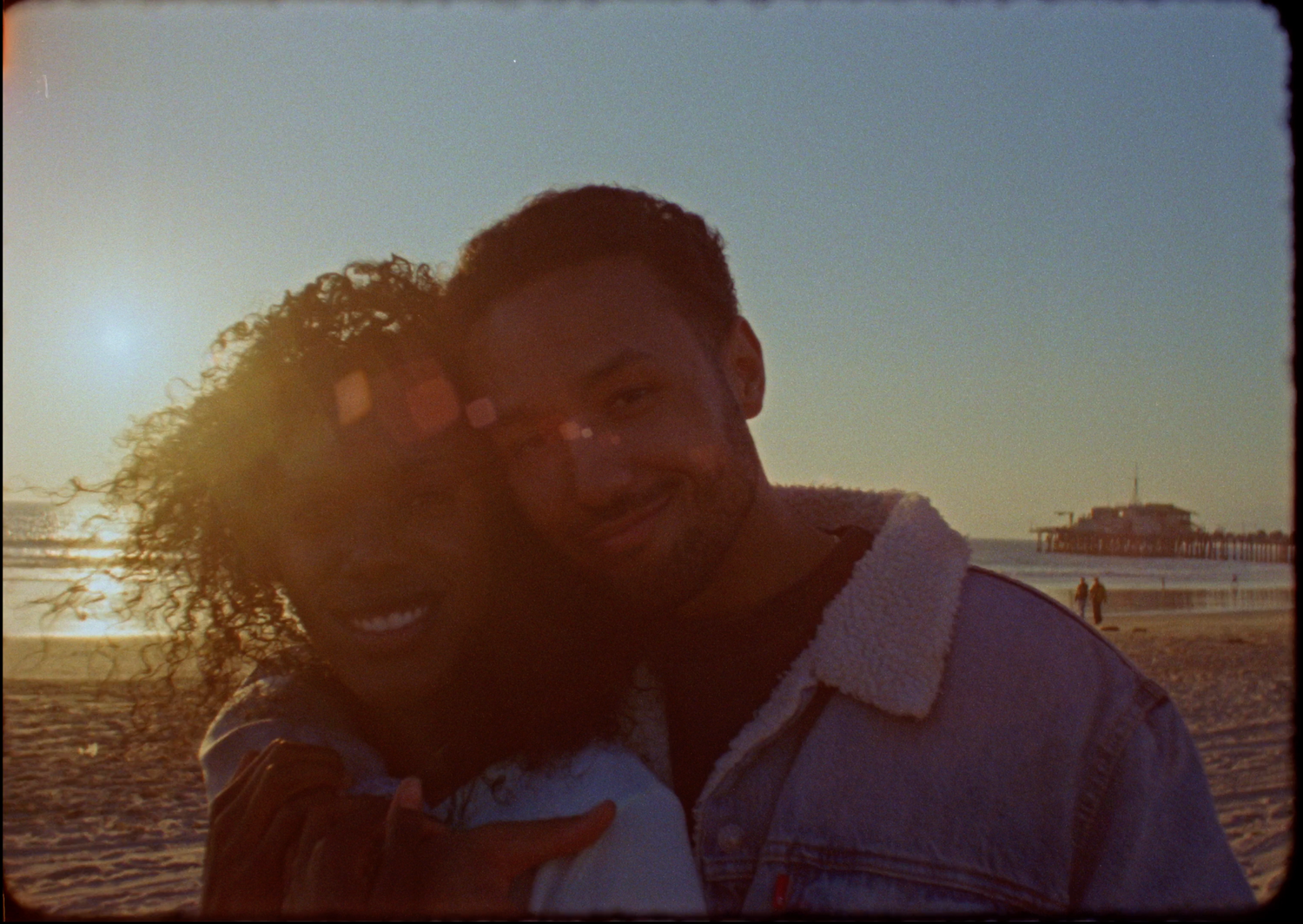 A couple shares a romantic silhouetted kiss at sunset with golden light streaming through their profiles.
