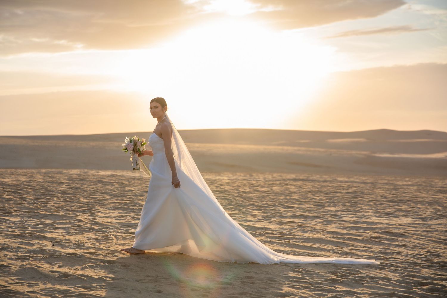 A dramatic sunset wedding photo session on a beach with flowing white dress.