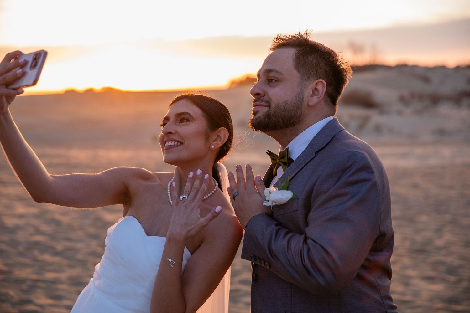 A couple shares a romantic moment at sunset on sandy terrain.